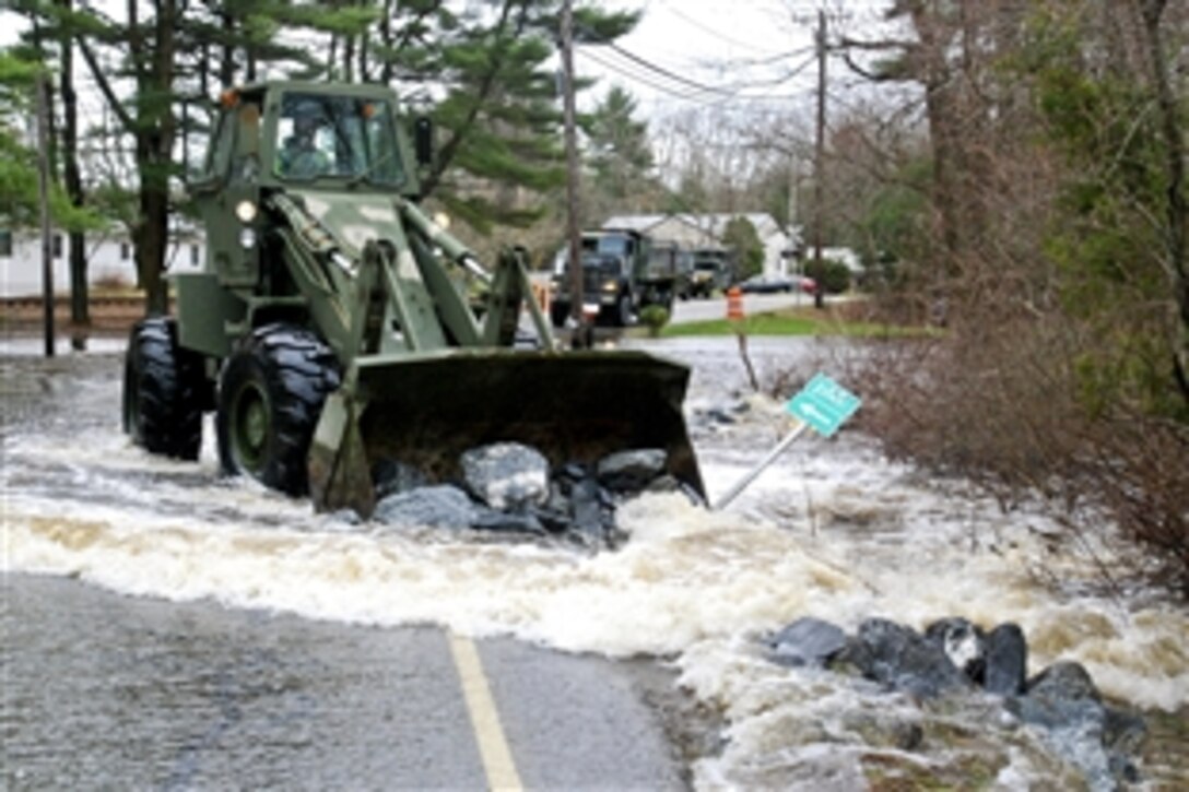 A U.S. Army soldier operates a front-end loader to preserve a flooded section of Beechwood Road in Freetown, Mass., March 31, 2010. The soldier is assigned to the the 189th Engineer Team, 101st Engineer Battalion, Massachusetts Nation Guard. The unit was activated to support Operation Rising Water, a statewide effort to aid communities affected by the flood. 