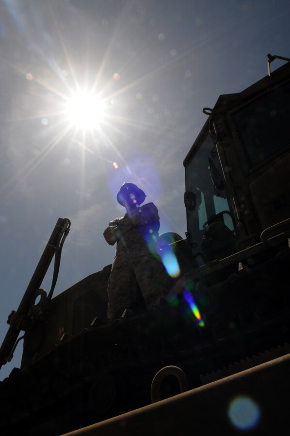 Lance Cpl. Danial Castaneda, Marine Wing Support Squadron 371 heavy equipment operator, stands on a medium crawler tractor awaiting instructions on what to clear next at Auxiliary Airfield 6 on April 3, 2010. The range is located 7 miles south of Gila Bend, Ariz. Castaneda, along with 13 other Marines from the squadron, worked for four days clearing 36,000 square feet of runway in support of the upcoming Weapons and Tactics Instructor course.