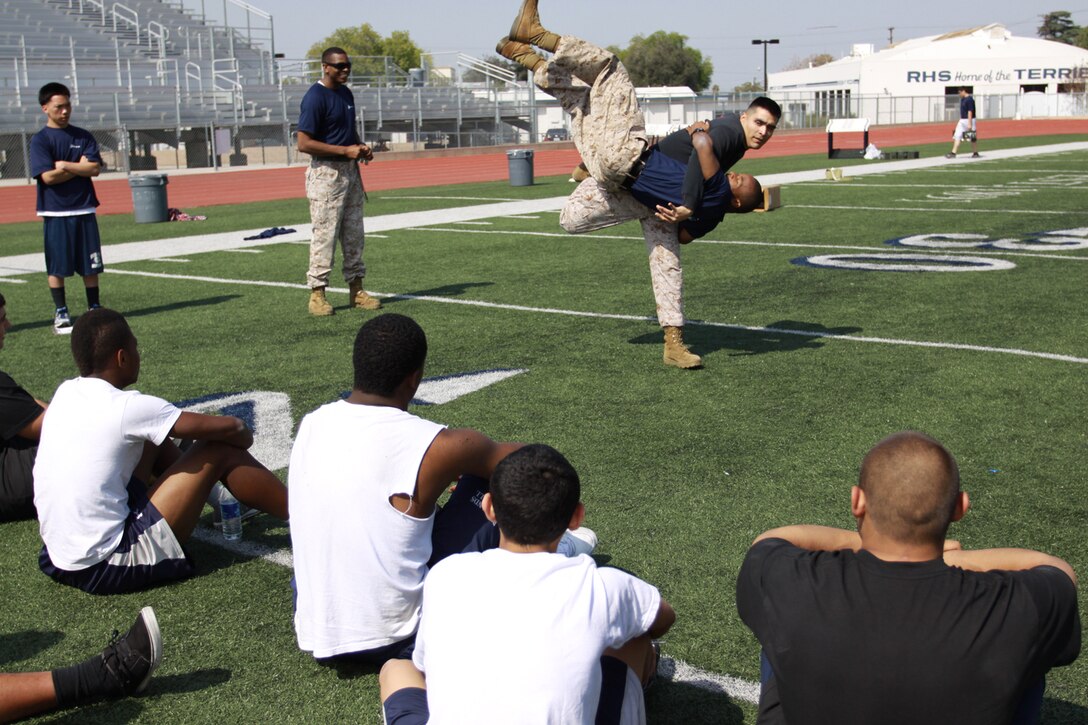 Staff Sgt. Juan Lopez, a canvassing recruiter from Recruiting Substation San Bernardino, Recruiting Station San Diego, demonstrates a sweeping hip through to football players from Redlands High School, Redlands, Calif.  The Marines conducted a leadership course to inspire the upcoming senior class to be better leaders.