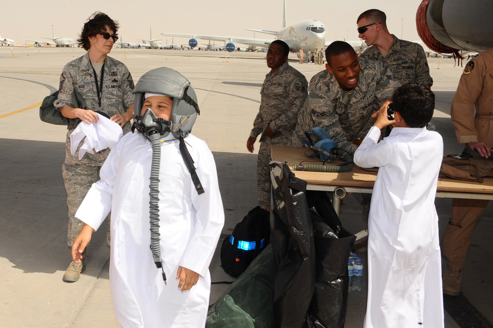 Host-nation children try on and look at B1-B Lancer aircrew flight equipment during Air Fest '10 at a non-disclosed Southwest Asia location April 1,2010. (U.S. Air Force photo by Senior Airman Kasey Zickmund)[RELEASED]