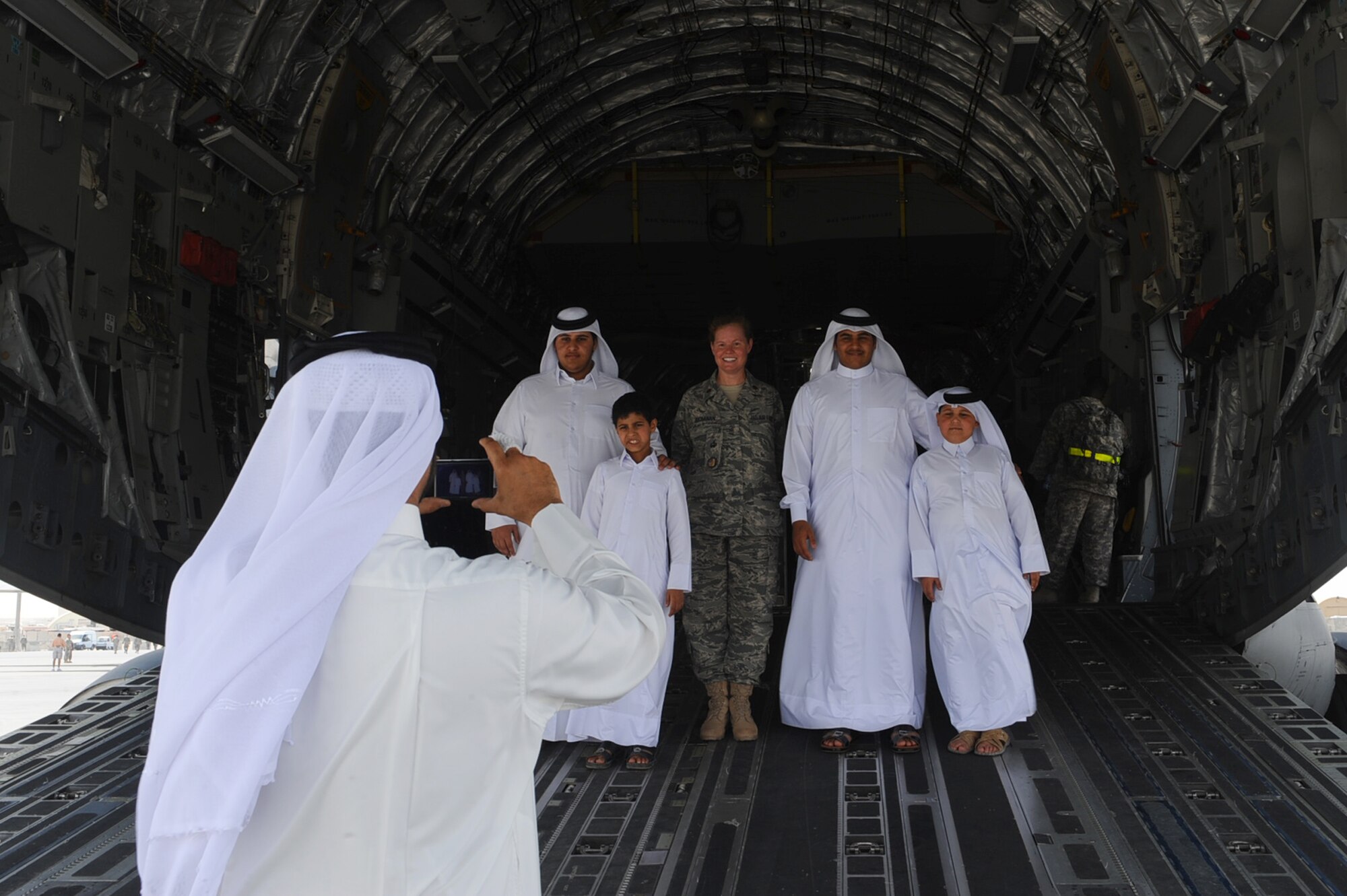 A host-nation member takes a picture of his sons and Maj. Docia Buchanan, 379th Air Expeditionary Wing Host-Nation Coordination Cell immigrations officer in-charge, in the back of a C-17 Globemaster during Air Fest '10 at a non-disclosed Southwest Asia location April 1, 2010. (U.S. Air Force photo by Senior Airman Kasey Zickmund)[RELEASED]