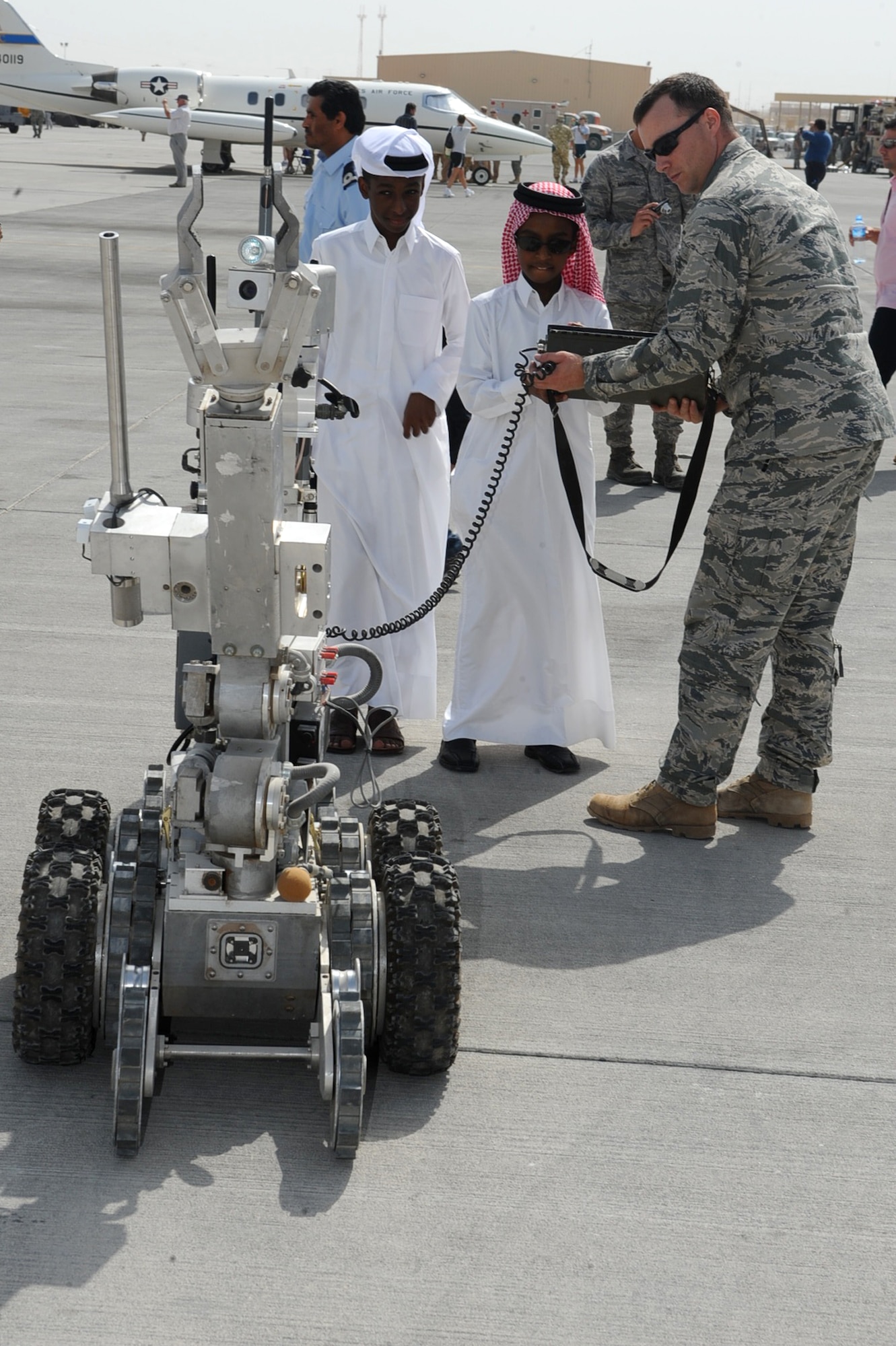 Staff Sgt. Tristan Brubacher, 379th Expeditionary Civil Engineer Squadron explosive ordinance disposal operator, holds the controls as a host-nation child controls an EOD robot during Air Fest '10 at a non-disclosed Southwest Asia location April 1, 2010. (U.S. Air Force photo by Senior Airman Kasey Zickmund)[RELEASED]