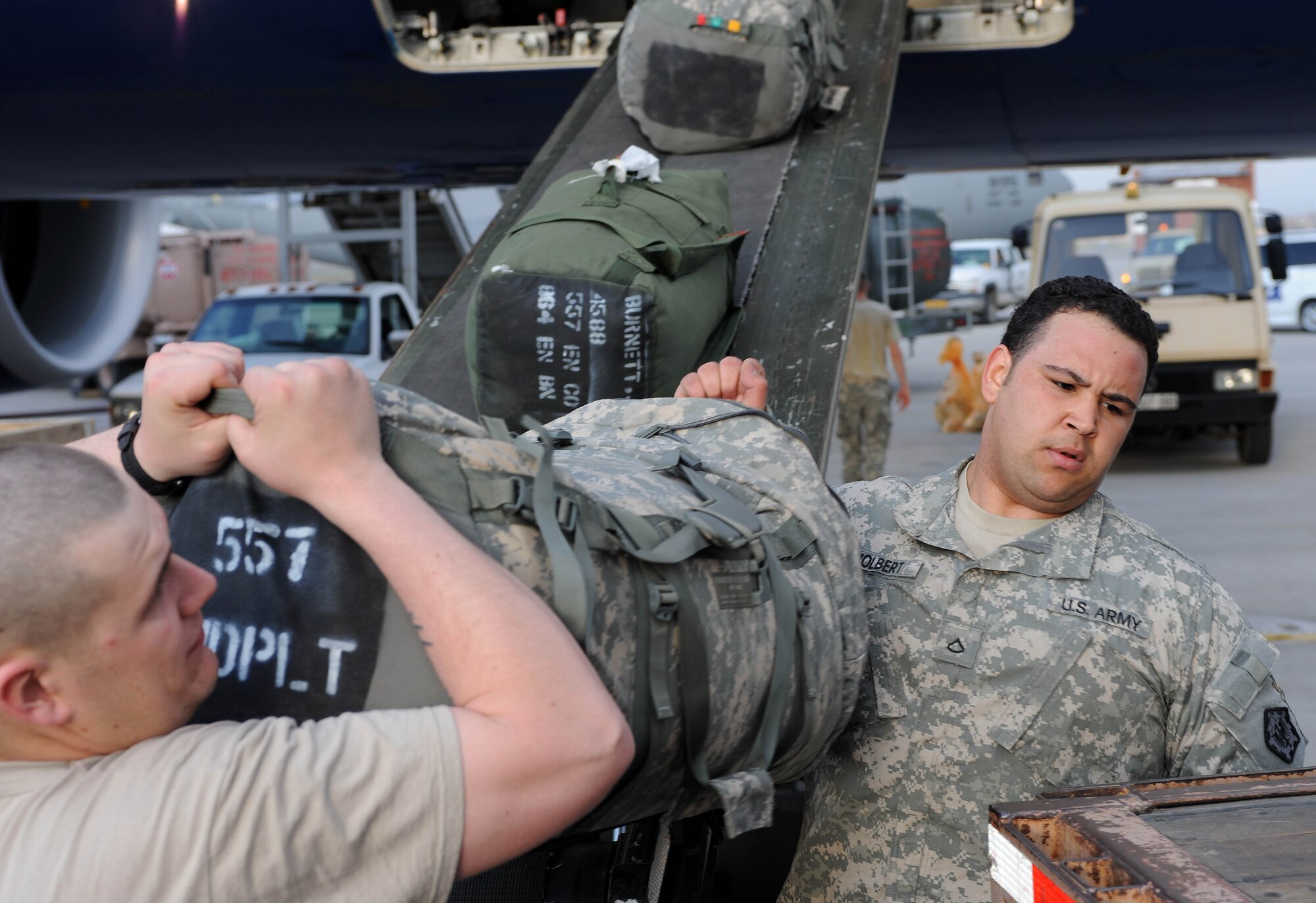 U.S. Army Private 1st Class Tyler Holbert and another Solider from the 557th Engineer Company, 864th Engineer Battalion, Ft. Lewis, Wash., load baggage onto a truck after arriving at the Transit Center at Manas, Kyrgyzstan, April 1, 2010. The Soldiers are en route Afghanistan. The 376th Expeditionary Logistics Readiness Squadron broke their own records in March for the most passengers moved through here, at the "gateway to Afghanistan."  (U.S. Air Force photo/Senior Airman Nichelle Anderson/released)