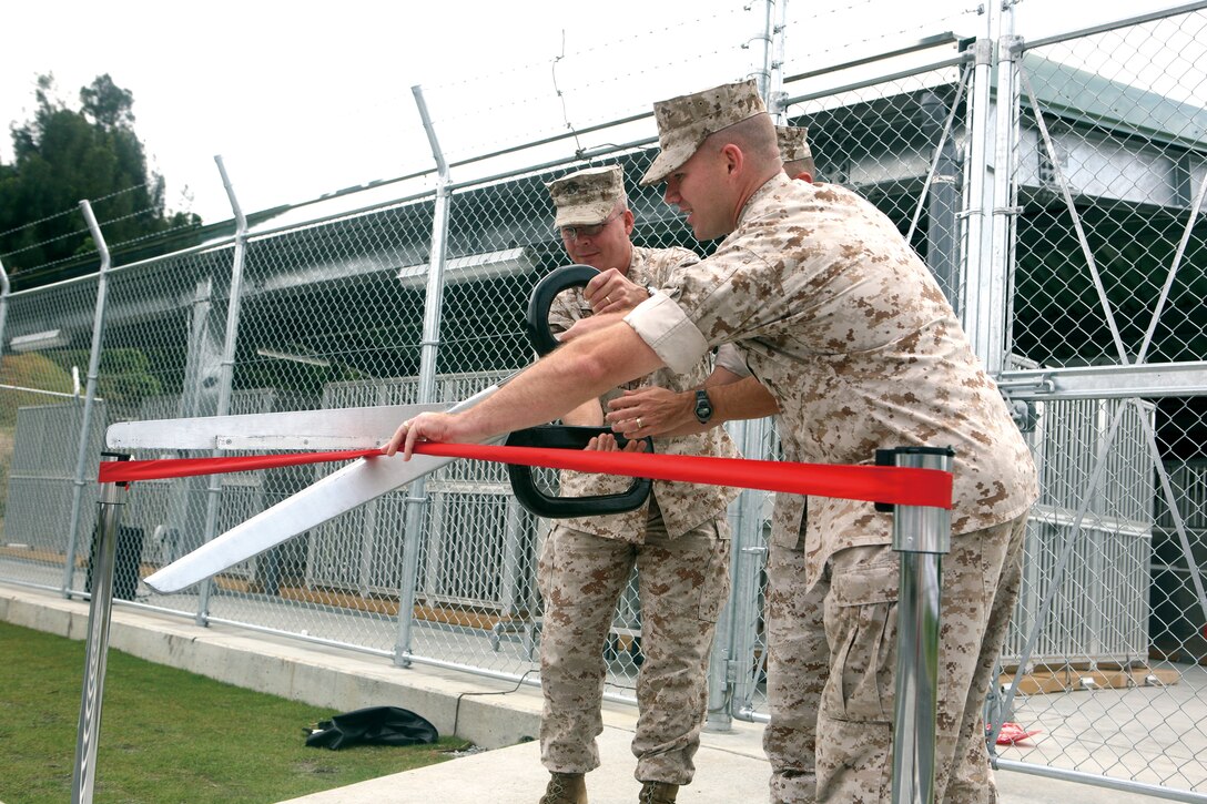 Lt. Col. J.D. Troutman, the III MEF Provost Marshal, left, Col. Dewey Jordan, III Marine Headquarters Group Co, middle, and Gunnery Sgt. Greg Ashby, kennel master for the new kennel cut the ribbon Monday for the new K-9 kennel on Camp Hansen. The kennel can hold up to 24 dogs assigned to III Marine Expeditionary Forces  Headquarters Group's newly formed Military Police  Support Company.