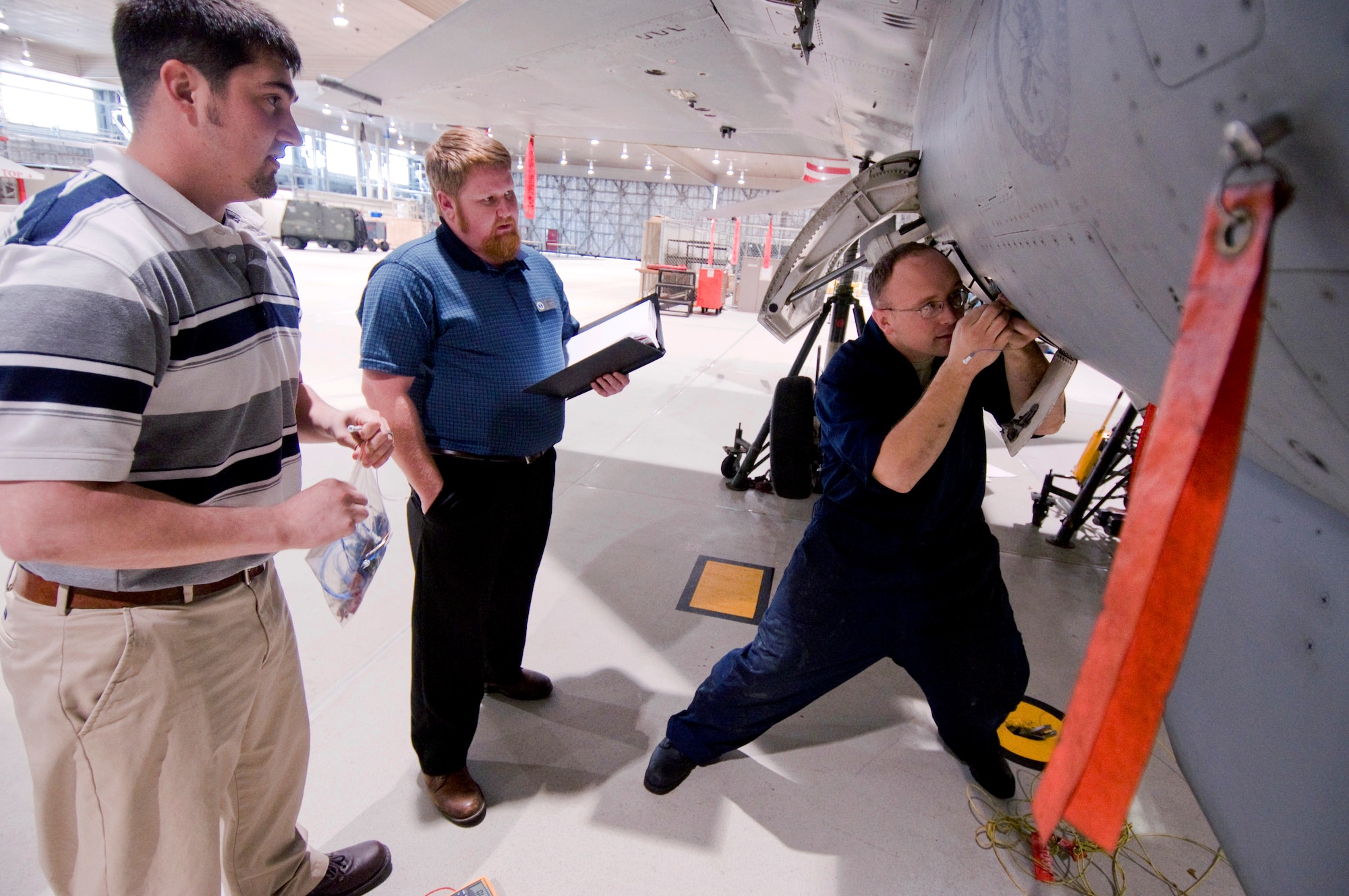 Staff Sgt. Jack Williams, 35th Aircraft Maintenance Squadron phase technician, fixes an exhaust gas temperature harness on a jet fuel starter while Robert Farnsworth and Richard Holmes Air Force Engineering and Technical Services technicians, provide over-the-shoulder assistance April 5, in Hangar 909. AFETS technicians provide technical support for aircraft maintainers when Airmen need assistance beyond their basic problem solving methods. (U.S Air Force photo/ Senior Airman Jessica Lockoski)  