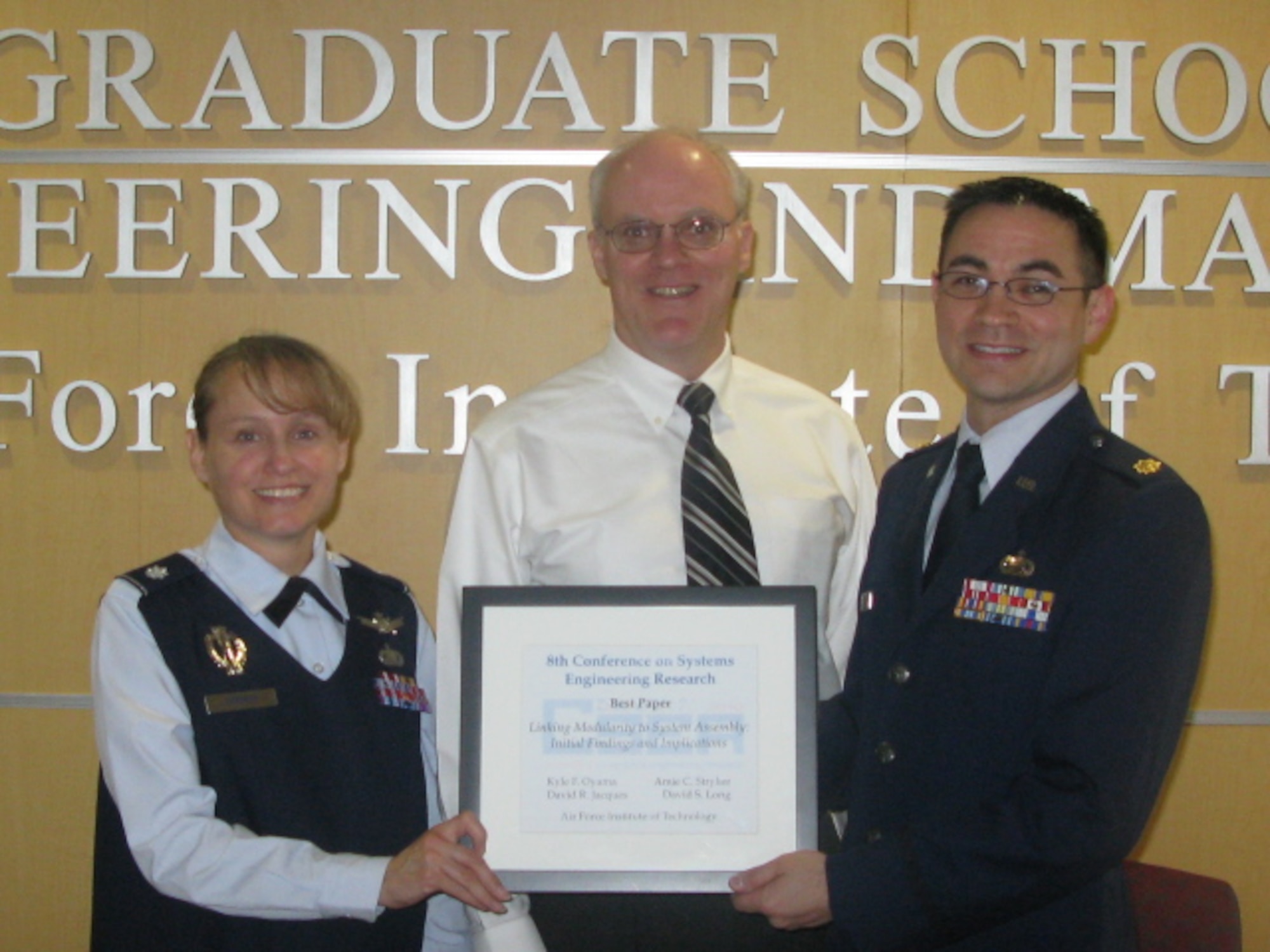 Lt. Col. Amie Stryker (left) is presented with her Best Paper Award by Dr. Dave Jacques (center) and Maj. Kyle Oyama (right), both from the Air Force Center for Systems Engineering at AFIT. Colonel Stryker won the award at the 8th Annual Conference of Systems Engineering Research (Air Force Photo by Karen Dobbyn)