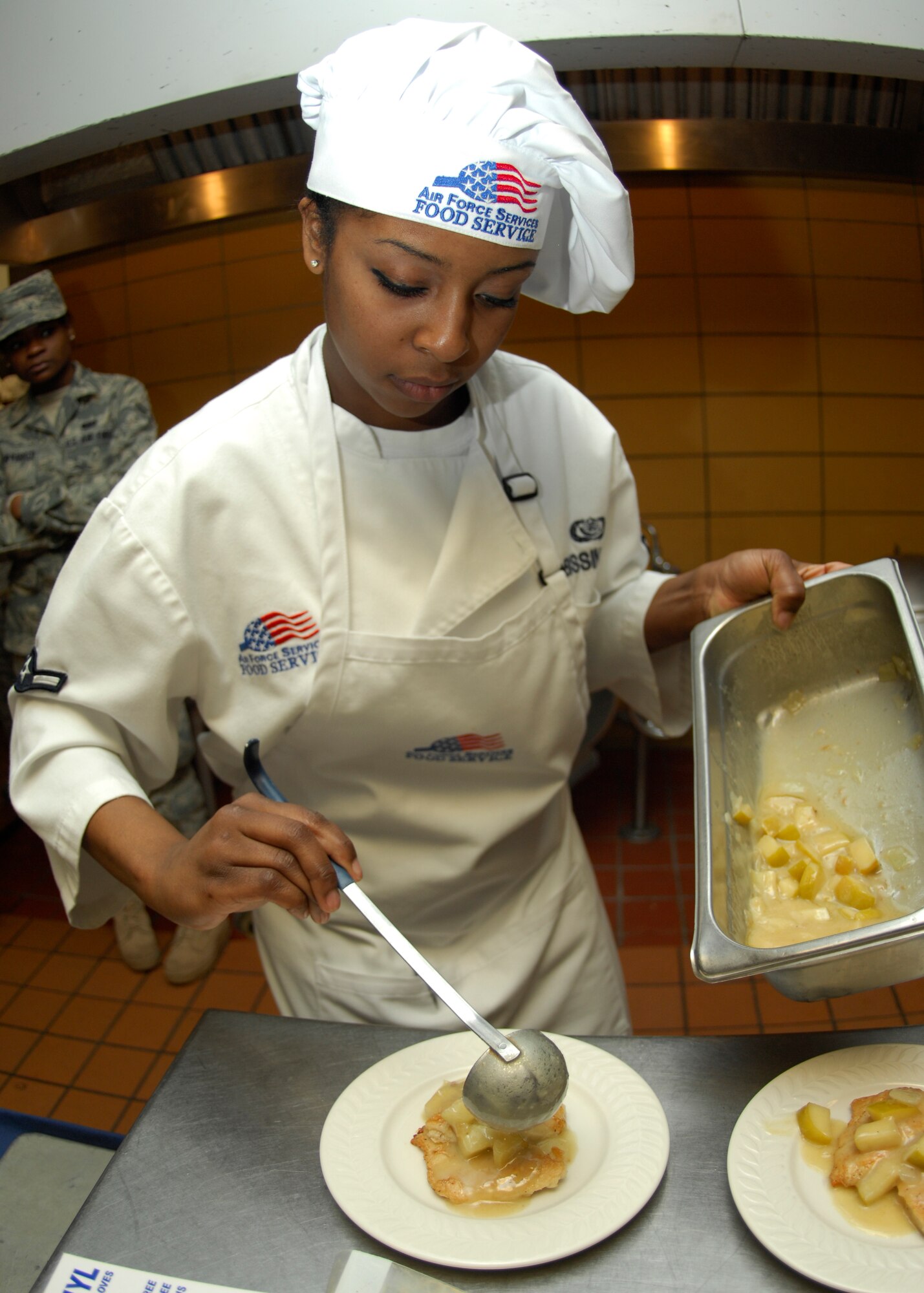 MINOT AIR FORCE BASE, N.D. -- Airman Brook Bissinger, 5th Bomb Wing Force Support Squadron services technician, pours an apple and pineapple sauce onto a piece of chicken breast during the 2010 Warrior Chef competition held at the Dakota Inn dining facility on Minot Air Force Base March 30.  The two teams were required to use a surprise ingredient, which was pineapple. (U.S. Air Force photo by Airman 1st Class Ashley N. Avecilla)
