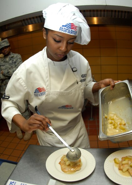 MINOT AIR FORCE BASE, N.D. -- Airman Brook Bissinger, 5th Bomb Wing Force Support Squadron services technician, pours an apple and pineapple sauce onto a piece of chicken breast during the 2010 Warrior Chef competition held at the Dakota Inn dining facility on Minot Air Force Base March 30.  The two teams were required to use a surprise ingredient, which was pineapple. (U.S. Air Force photo by Airman 1st Class Ashley N. Avecilla)