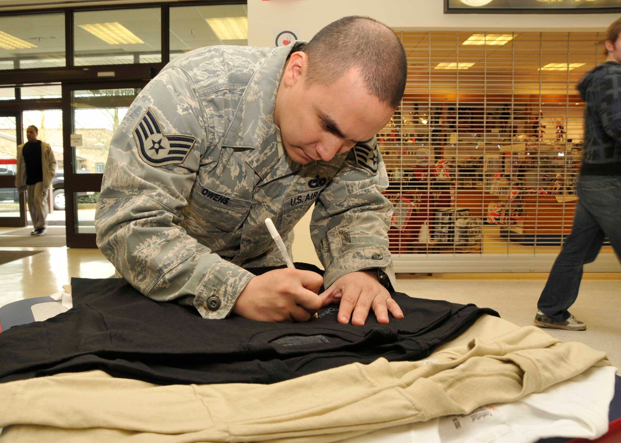 Staff Sgt. David Owens, 100th Refueling Wing 727th Aircraft Maintenance Squadron services manager, signs a Sexual Assault Awareness t-shirt at the base exchange at RAF Lakenheath, England, April 5. These t-shirts will be hung in the base commissary for display during the Sexual Assault Awareness Month. For more information see the related link Lakenheath community bulletins.
 (U.S. Air Force Photo/Airman 1st Class Eboni Knox)