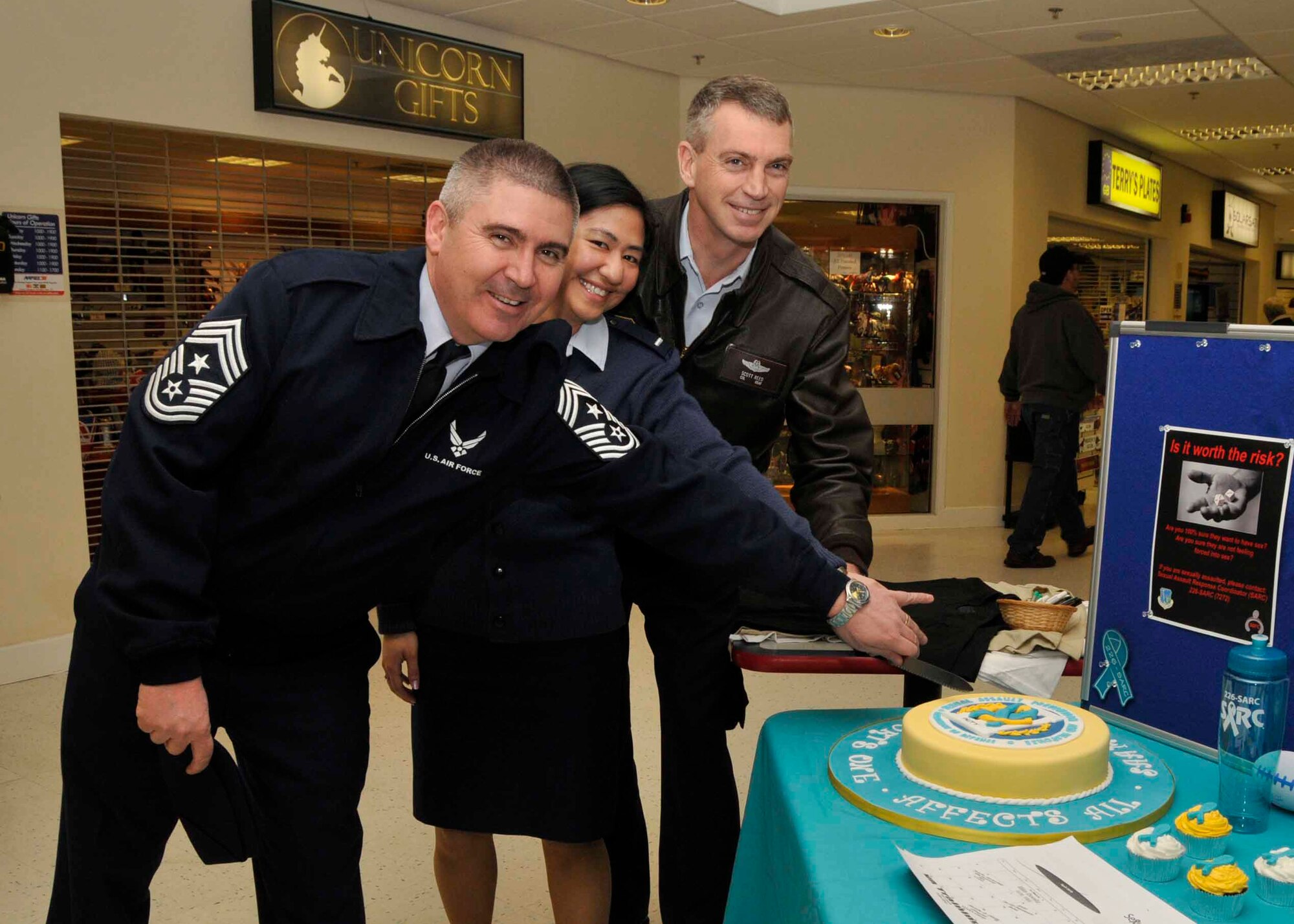 Col. Lawrence Reed, 48th Fighter Wing vice commander(right), 1st Lt. Angela Naval, 48th Fighter Wing Sexual Assault Response Coordinator(middle) and Chief Master Sergeant James Lucas, 48th Fighter Wing command chief(left), cut the cake during the 2010 Sexual Assault Awareness Month kick-off at the base exchange at RAF Lakenheath, England, April 5. For more information see the related link Lakenheath community bulletins. (U.S. Air Force Photo/Airman 1st Class Eboni Knox)