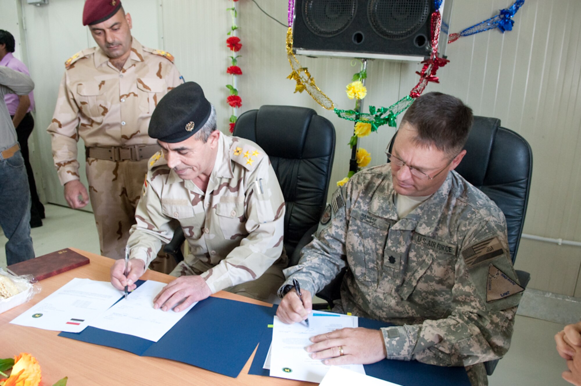 U.S. Air Force Lt. Col. Steven Ramsay, senior advisor, Logistics Military Advisory Team, Joint Expeditionary Tasking Airman assigned to the U.S. Army, 4th Brigade Combat Team 1st Armored Division, COB Adder and Iraq Army Staff Brig. Gen. Hassan, location commander, Camp Ur, officially sign the papers that hand-over Camp Ur to the Iraq Army March 28, 2010. Camp Ur, is a 15 month project  by coalition forces and ALMCO, an Iraqi company who built a warehouse, numerous barracks, offices, latrines and a large dining facility for the location command and training center.  (U.S. Air Force Photo/Senior Master Sgt. Elizabeth Gilbert. Released)