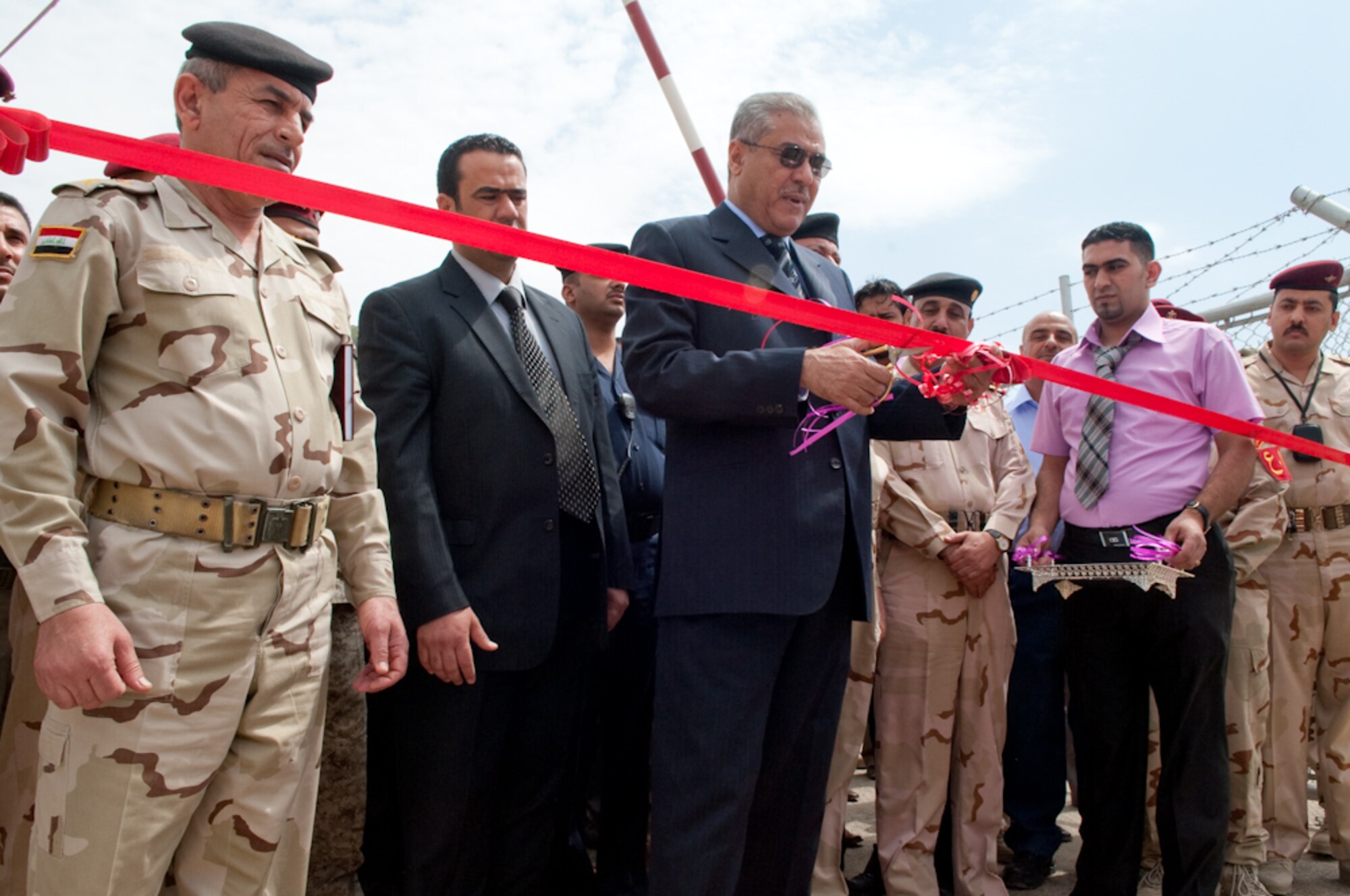 The Governor of the Dhi Qar Province, Iraq, along with Iraq Staff Brig. Gen Hassan, location commander for Camp Ur, cuts the ribbon to officially open the brand new facility built by ALMCO,  a local contractor, overseen by the U.S. Army Corps of Engineers and facilitated by the Logistics Military Advisory Team at Camp Ur, Iraq, March 28, 2010. Distinguished Visitors, U.S and coalition forces gathered together for a formal ribbon cutting ceremony, celebrating 15 months of work by coalition forces and ALMCO, an Iraqi company at Camp Ur.  (U.S. Air Force Photo/Senior Master Sgt. Elizabeth Gilbert. Released)
