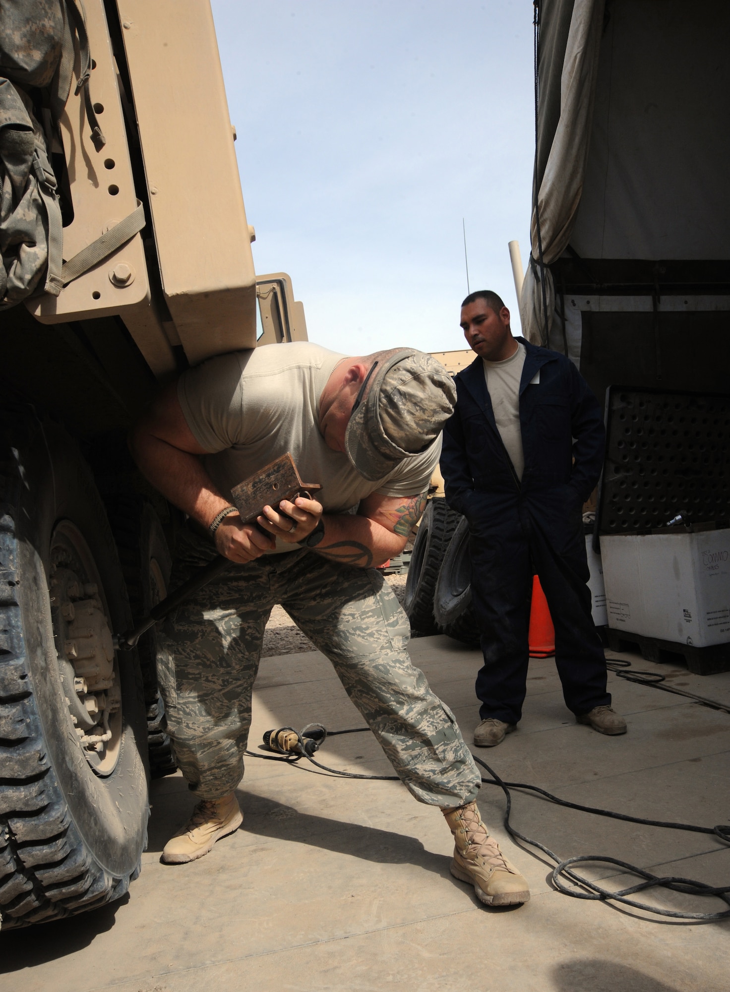 Air Force Staff Sgt. Juan Hurtado (right), 732nd Expeditionary Security Forces Squadron, maintenance technician, oversees Staff Sgt. Jason Evans, while he manually removes a lug nut on an Mine Resistant Ambush Protected vehicle tire, Camp Stryker, Iraq, March 25, 2010.  There is always a qualified vehicle maintainer watching to make sure everything is done correctly. (U.S. Air Force photo/Master Sgt. Trish Bunting/Released)