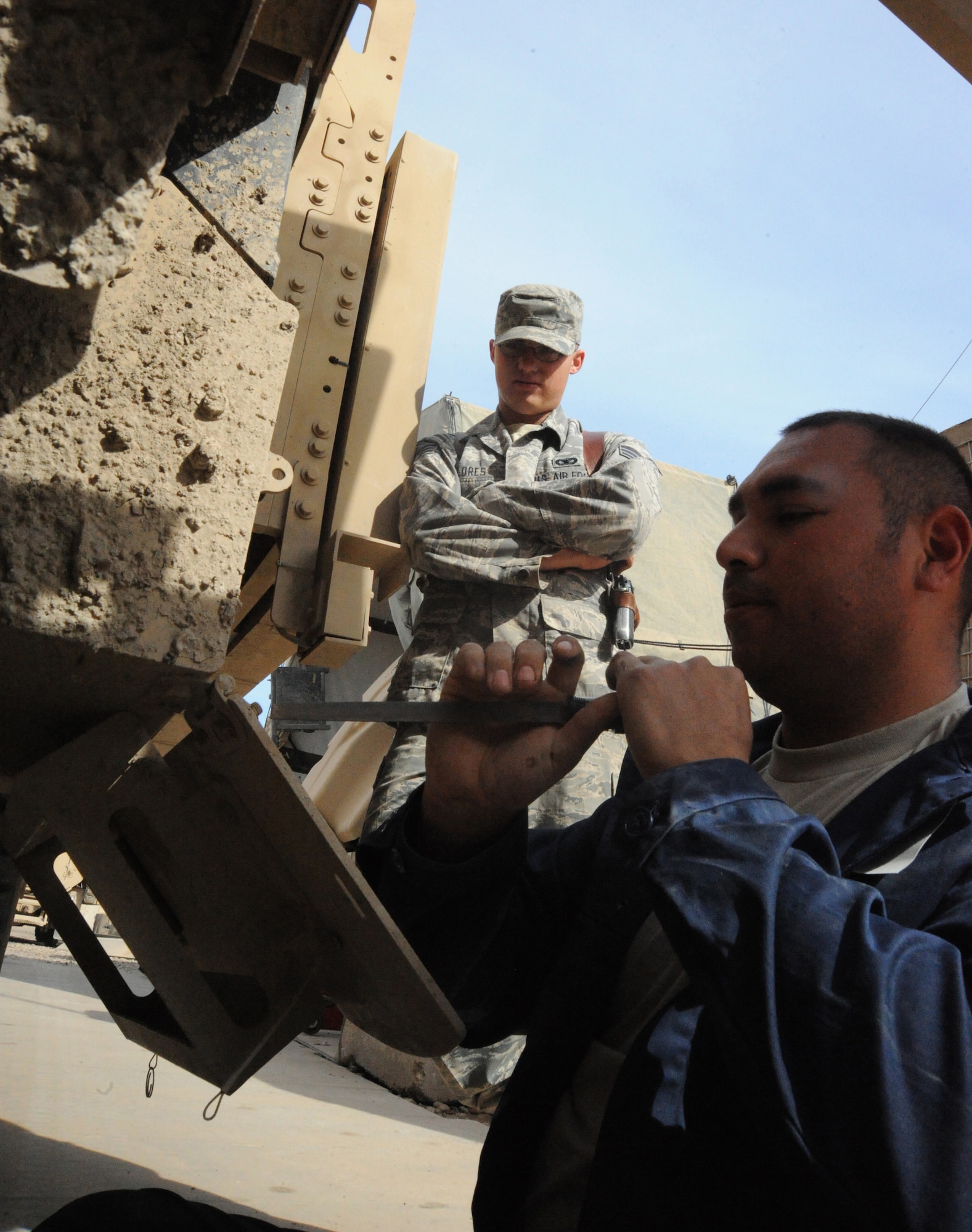 Air Force Staff Sgt. Juan Hurtado (right), 732nd Expeditionary Security Forces Squadron maintenance technician, shows Senior Airman Richard Flores how to fix a common maintenance issue on an Mine Resistant Ambush Protected vehicle hatch, Camp Stryker, Iraq, March 25, 2010. Before each inspection, the “Reapers” go through a checklist that includes checking the oil, tire pressure and searching for leaks. There is always a qualified vehicle maintainer watching to make sure everything is done correctly. (U.S. Air Force photo/Master Sgt. Trish Bunting/Released)