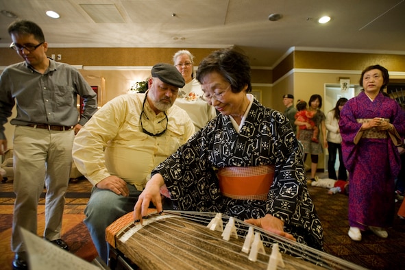 Kazu Suzuki shows Bryan Perdue, 35th Civil Engineer Squadron base planner, how to play the koto during the 23rd Annual Japan Day April 3, 2010, at the Misawa Collocated Club, Misawa Air Base, Japan. Mrs. Suzuki is a koto student who volunteered to play the traditional Japanese instrument during this year's event. (U.S. Air Force photo/Senior Airman Jamal D. Sutter) 