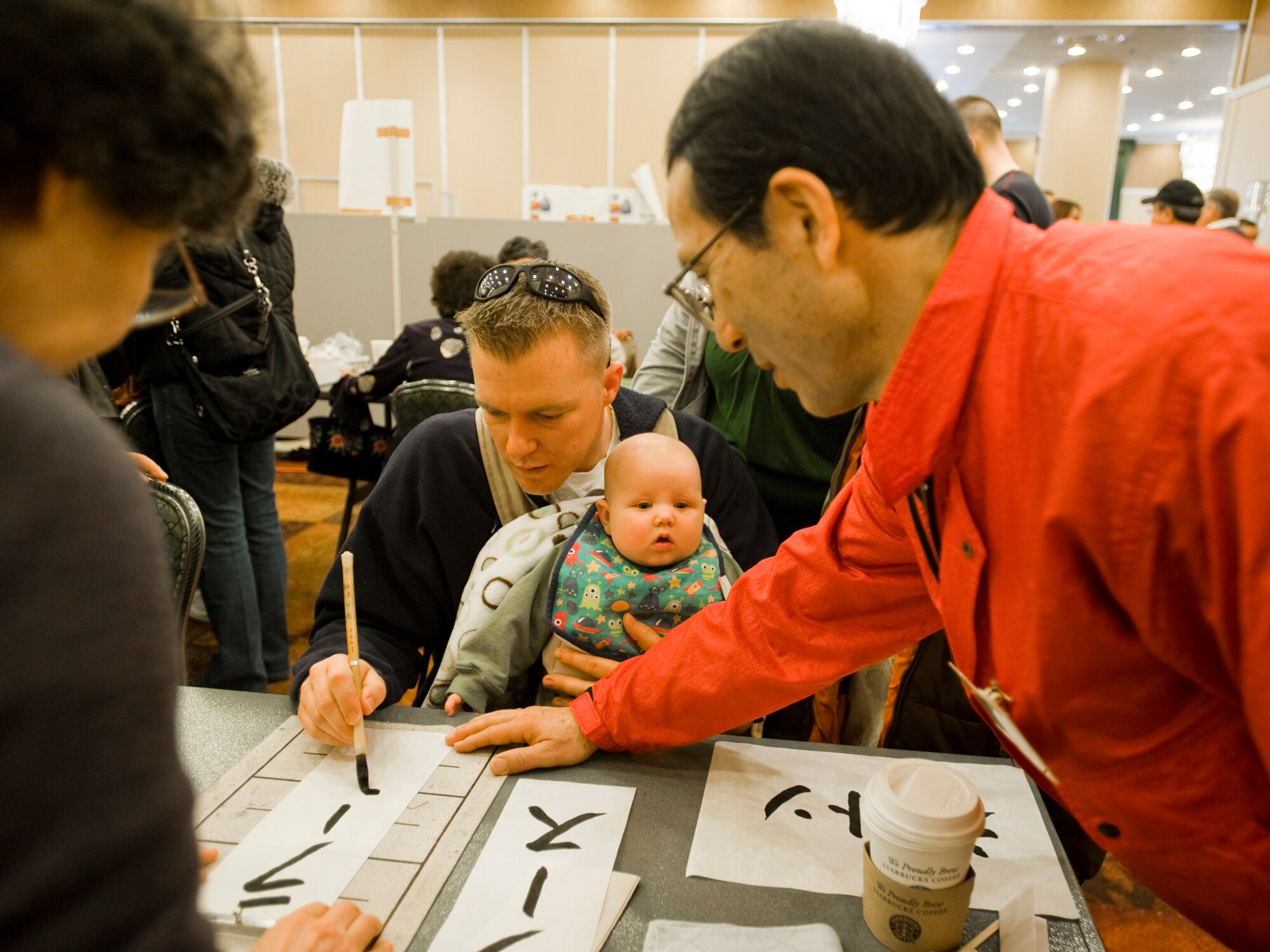MISAWA AIR BASE, Japan -- Chief Petty Officer Janssen Jascha, of Combined Task Force 72, follows Yashiro Takebayashi's guidance during a calligraphy lesson as part of the 23rd Annual Japan Day April 3 at the Misawa Collocated Club. Chief Jascha spelled the name of his son, Lars, using Japanese Katakana characters. (U.S. Air Force photo/Senior Airman Jamal D. Sutter)