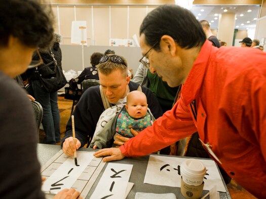 Chief Petty Officer Janssen Jascha, of Combined Task Force 72, follows Yashiro Takebayashi's guidance during a calligraphy lesson as part of the 23rd Annual Japan Day April 3, 2010, at the Misawa Collocated Club, Misawa Air Base, Japan. Chief Jascha spelled the name of his son, Lars, using Japanese Katakana characters. (U.S. Air Force photo/Senior Airman Jamal D. Sutter) 