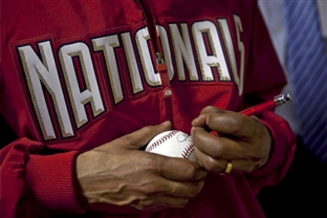 President Barack Obama signs a baseball after throwing out the ceremonial first pitch on opening day of the Major League Baseball season at Nationals Park in Washington, D.C., April 5, 2010.
