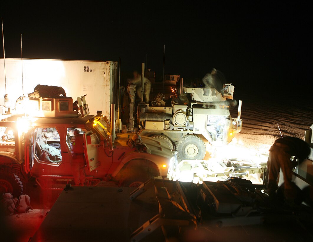 Prior to embarking on their journey back to Camp Leatherneck, the staging area bustles with activity as Marines from Combat Logistics Battalion 6, 1st Marine Logistics Group (Forward) prepare their gear and vehicles during the predawn hours of April 5. The Marines led a convoy of more than 200 vehicles in support of the British to American transfer of authority here.