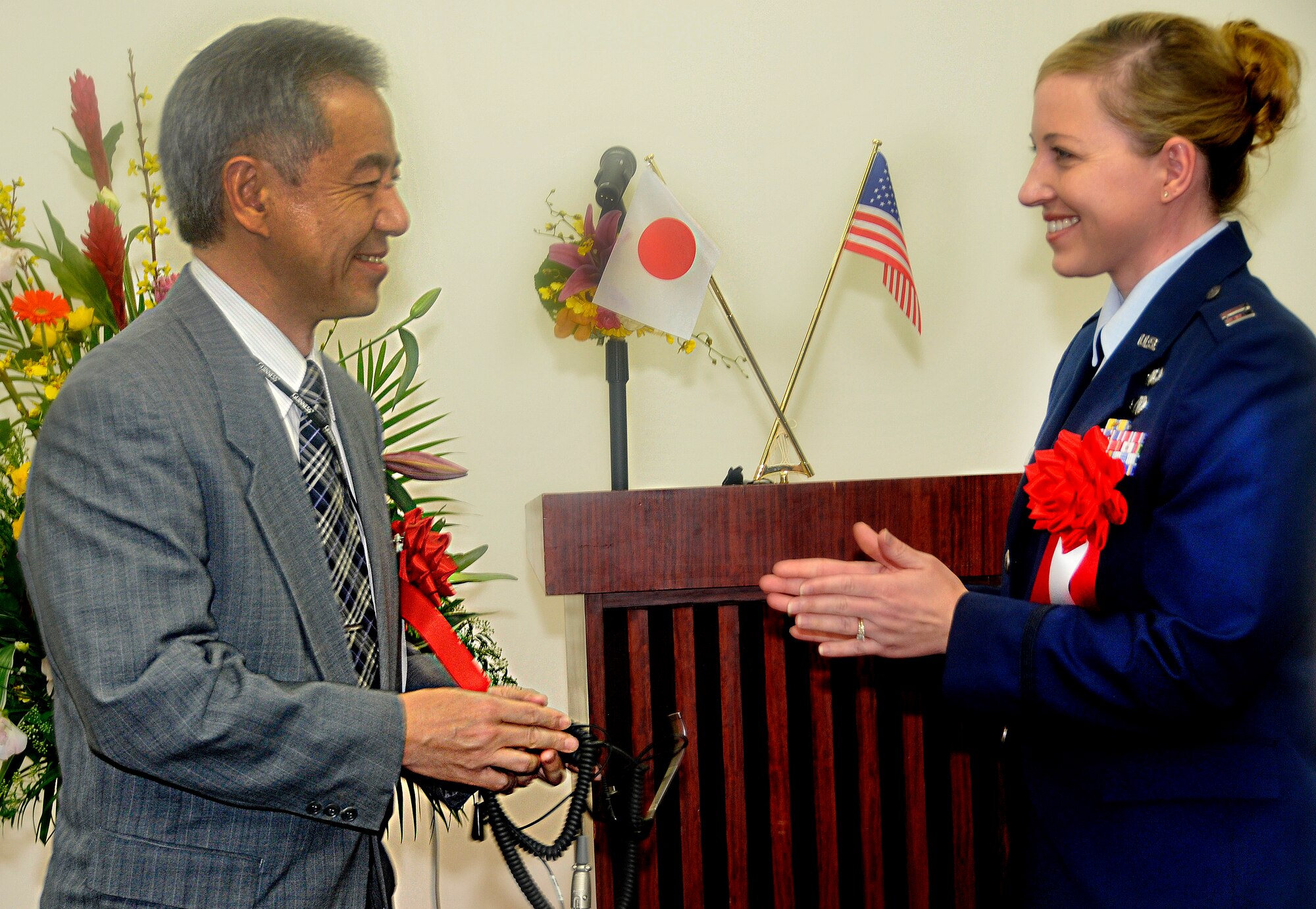 Mr. Masahiro Muroya, Director General, Okinawa Air Traffic Services Department, and Capt. Brooke Kelly, Kadena Airfield Operations flight commander, exchange a symbolic air traffic controller headset at a ceremony marking the reversion of Kadena radar approach control to the Japanese. The RAPCON transfer ceremony took place at Naha Airport, Okinawa, March 30. (U.S. Air Force photo / Airman 1st Class Jarvie Wallace)