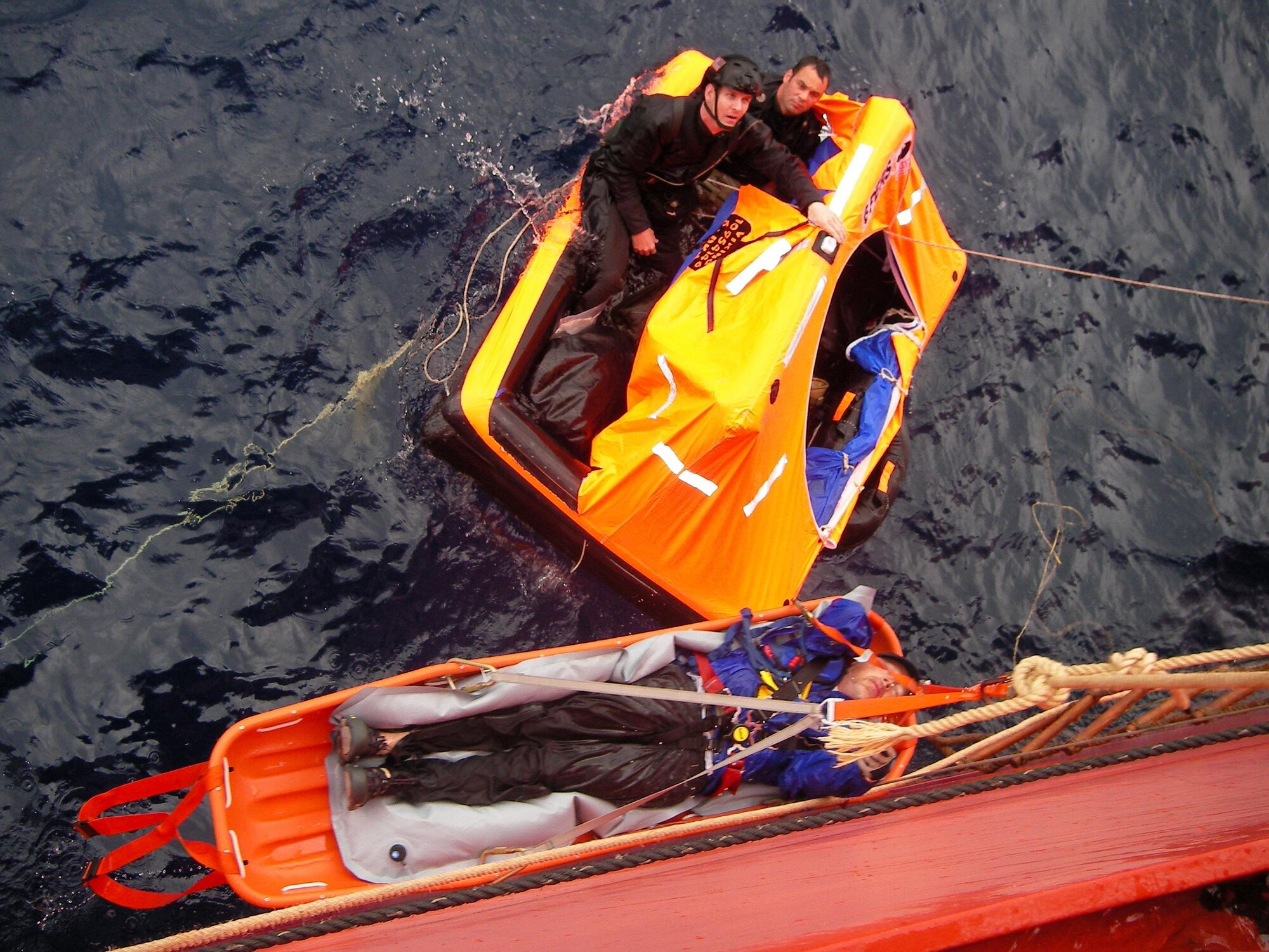 Pararescuemen from the 129th Rescue Wing transfer a patient to a container vessel April 2, 2010. The Eleventh Coast Guard District Rescue Coordination Center used their Automated Mutual Assistance Vessel Rescue system to divert a Liberian registered merchant vessel, the CAP PALMERSTON, enroute to Ensenada, Mexico, to rendezvous with the sailing vessel and pick-up the PJs and their patient. The AMVER program is sponsored by the U.S. Coast Guard and is a voluntary global ship reporting system used worldwide by search and rescue authorities to arrange for assistance to persons in distress at sea. Following the transfer of the patient and PJs from the small sailboat to the CAP PALMERSTON, the ship set course to San Diego. The patient and PJs were picked up by 129th rescue crews April 4, 2010. (Photo courtesy of the CAP PALMERSTON crew.)