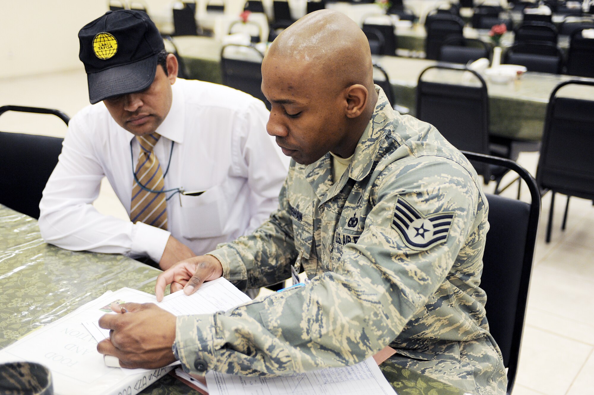 Staff Sgt. William Crenshaw reviews comments with the manager of Dining Facility Two at Joint Base Balad, Iraq, March 23, 2010, after a successful inspection of the facility.  Sergeant Crenshaw is the 332nd Aerospace Medical Squadron public health noncommissioned officer in charge and is deployed from Lackland Air Force Base, Texas. (U.S. Air Force photo/Master Sgt. Linda C. Miller)