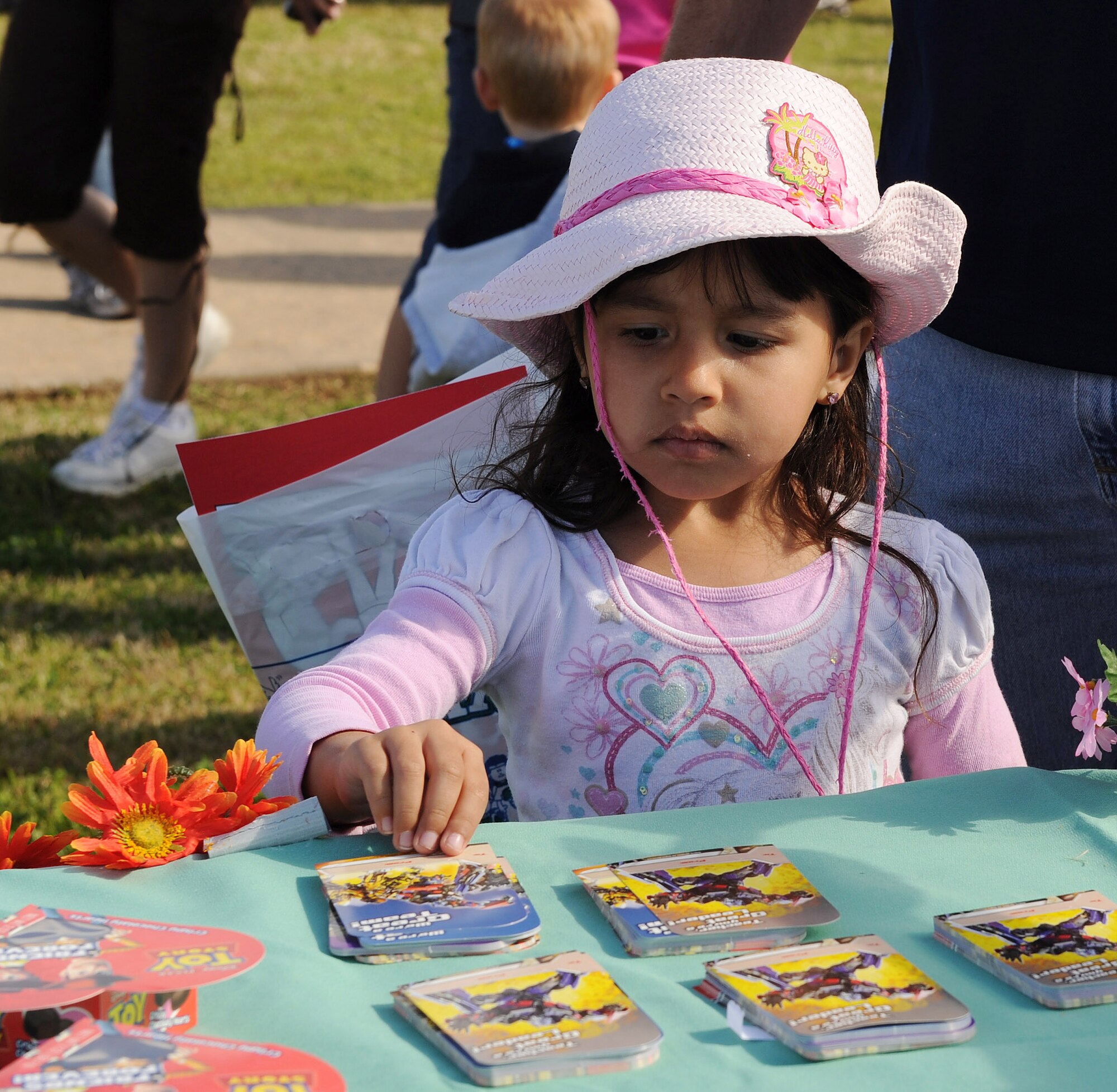 Andrea Galloway, 4, daughter of Tech. Sgt. Randall Galloway, 19th Logistics Readiness Squadron fuel lab supervisor, and Brenda Galloway, picks up a card given to the children as they enter the “It’s All About YOUth” festival and egg hunt April 3. The festival had events and activities that included an egg hunt, bouncy castles, laser tag, face painting, McGruff the Crime Dog, games, giveaways and crafts for families to enjoy. (U.S. Air Force photo by Staff Sgt. Chad Chisholm)