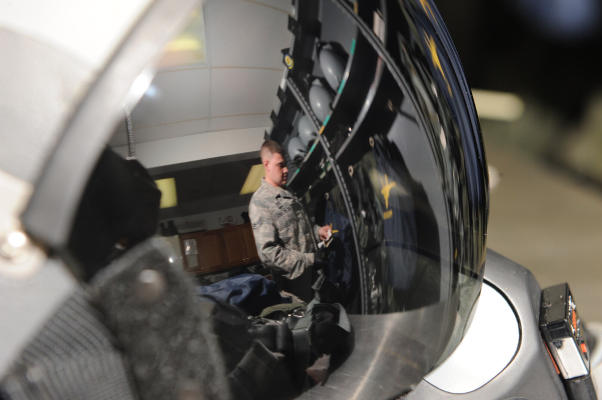 JOINT BASE PEARL HARBOR-HICKAM, Hawaii - The image of Senior Airman Kenny Moylan, an aircrew flight equipment journeyman with the 19th Fighter Squadron, Elmendorf AFB, Alaska, is reflected as he checks the safety equipment of the pilots that he works with everyday while at Joint Base Pearl Harbor-Hickam on March 23.  Airman Moylan is supporting the 19th FS pilots while they participate in training exercise with the 199th FS of the Hawaii Air National Guard. (Air Force photo by Tech. Sgt. Cohen A. Young)