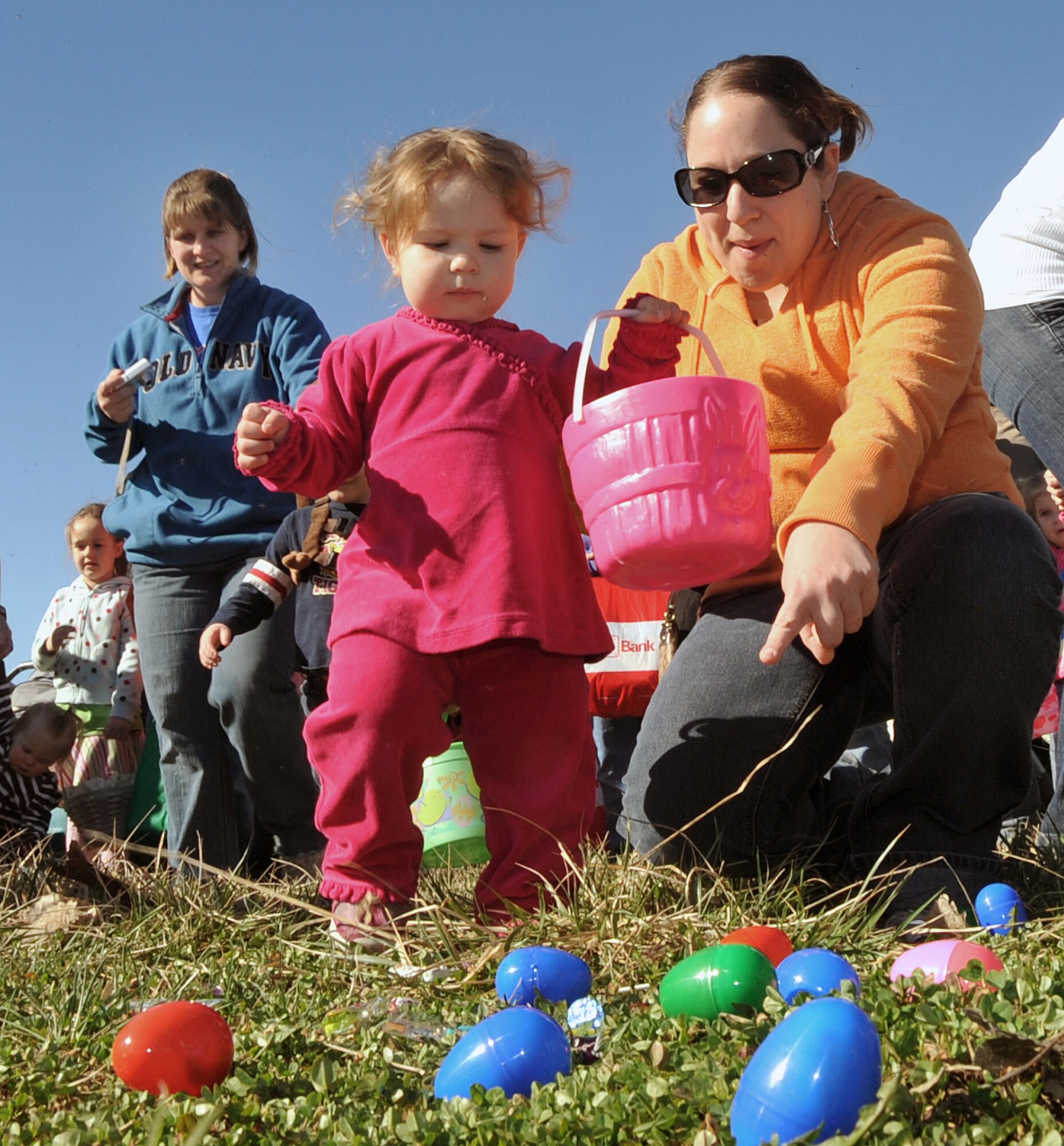OFFUTT AIR FORCE BASE, Neb. -- Danielle Farnum, the wife of Tech. Sgt. Eric Farnum with U.S. Strategic Command, shows her daughter Jaelyn, where to pick up Easter eggs at Offutt's annual Easter egg hunt at the Base Lake April 3. The event was one of several military families took part in during the holiday weekend. U.S. Air Force Photo by Jeff W. Gates