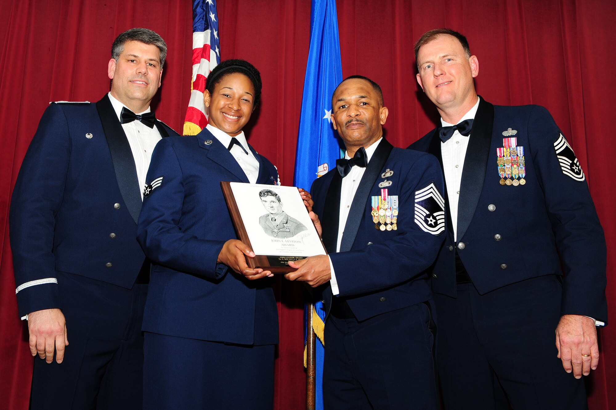 Senior Airman Michelle Bell, 19th Force Support Squadron, (left center) is presented the John Levitow Award by Col. Greg Otey, 19th Airlift Wing commander, Chief Master Sgt. Stephen Gregory, 19th Comptroller Squadron, and Chief Master Sgt. Jimmy Daniels, 19th FSS, April 2 at the Thomas Community Activities Center. The Levitow Award is presented to the top performing Airmen in each class at Airman Leadership School. (U.S. Air Force Photo by Senior Airman Steele C. G. Britton)