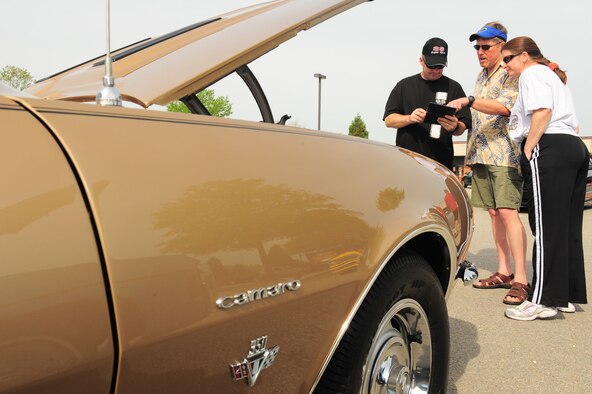 SHAW AIR FORCE BASE, S.C. -- Mike Madsen (middle) and Master Sgt. Marsha Madsen, 20th Force Support Squadron Airman and Family Readiness Center readiness NCO-in-charge, show off their 1967 Chevy Camaro SS to Major Terry Wanner, 20th Component Maintenance Squadron operations officer, during a car show here April 3. The 2010 Shaw Car Show was sponsored by the Army and Air Force Exchange Service. (U.S Air Force photo/Senior Airman David Minor)