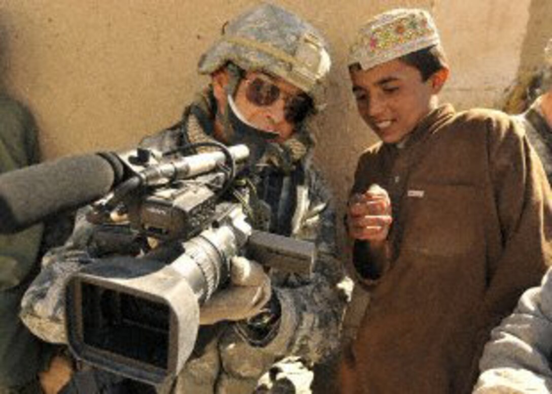 U.S. Air Force Master Sgt. Robert Carreon, a videographer with 4th Combat Camera Squadron, March Air Reserve Base, Calif.,  shows an Afghan student his footage at the Bazaar school in Hutal, Afghanistan, Jan. 7, 2010.  Sergeant Carreon was attached to the 5th Brigade, 2nd Infantry Division.  (U.S. Air Force photo/Staff Sgt. Dayton Mitchell) 
