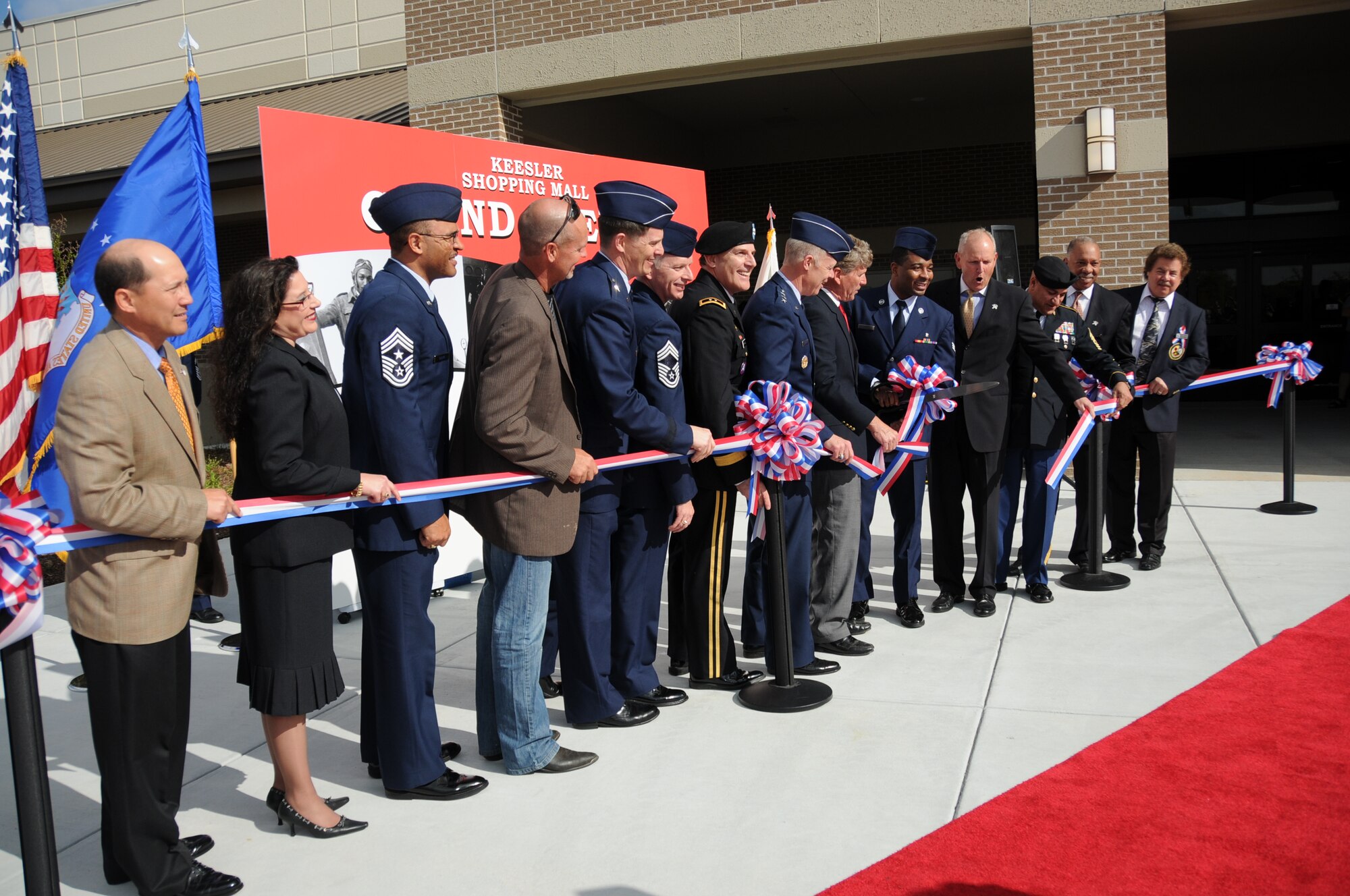 Senior Airman Brandon Ailes, fifth from right, is flanked by Army and Air Force Exchange Service, Defense Commissary Agency, Keesler and community leaders as he cuts the ribbon on the base’s new shopping mall Tuesday. Airman Ailes, 81st Medical Operations Squadron, is Keesler’s Airman of the Year.  (U.S. Air Force photo by Kemberly Groue)