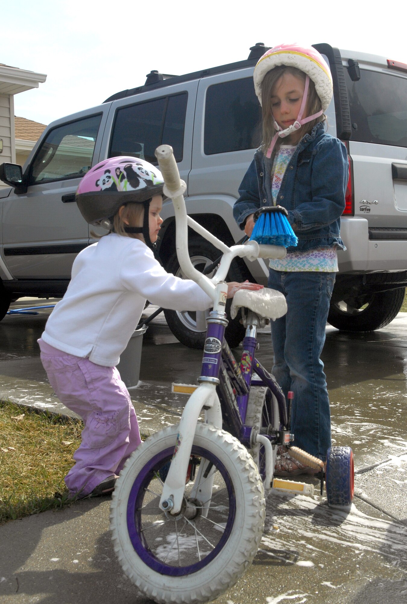 MINOT AIR FORCE BASE, N.D. -- Morgan Jenner, 5, and Lani Akin, 2 wash their bicycles while the Akin family washes their car April 7 as they get excited about Spring's appearance at Minot AFB.  With the recent warmer weather, members and families at Minot AFB have begun to enjoy outdoor activities again. (U.S. Air Force photo by Laurie Arellano)