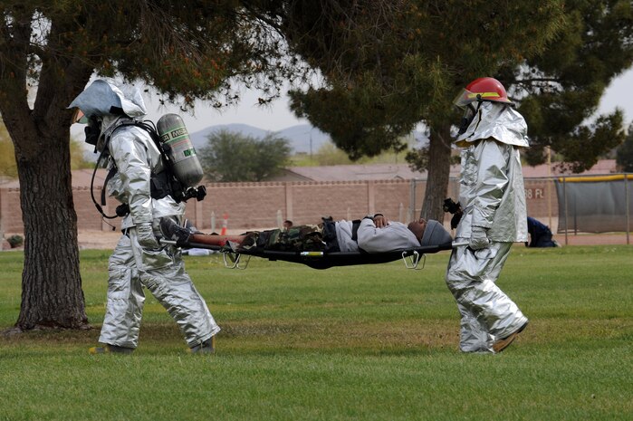 NELLIS AIR FORCE BASE, NEV. - 99th Civil Engineering Squadron fire fighters carries a victim back to the DECON center during the All Hazard Response Exercise, March 25. The All Hazard Response Exercise tested first responders throughout the 99th Air Base Wing, including Security Forces, Explosive Ordnance Disposal, and hospital personnel.  (U.S. Air Force Photo by Airman 1st Class Brett Clashman/RELEASED)