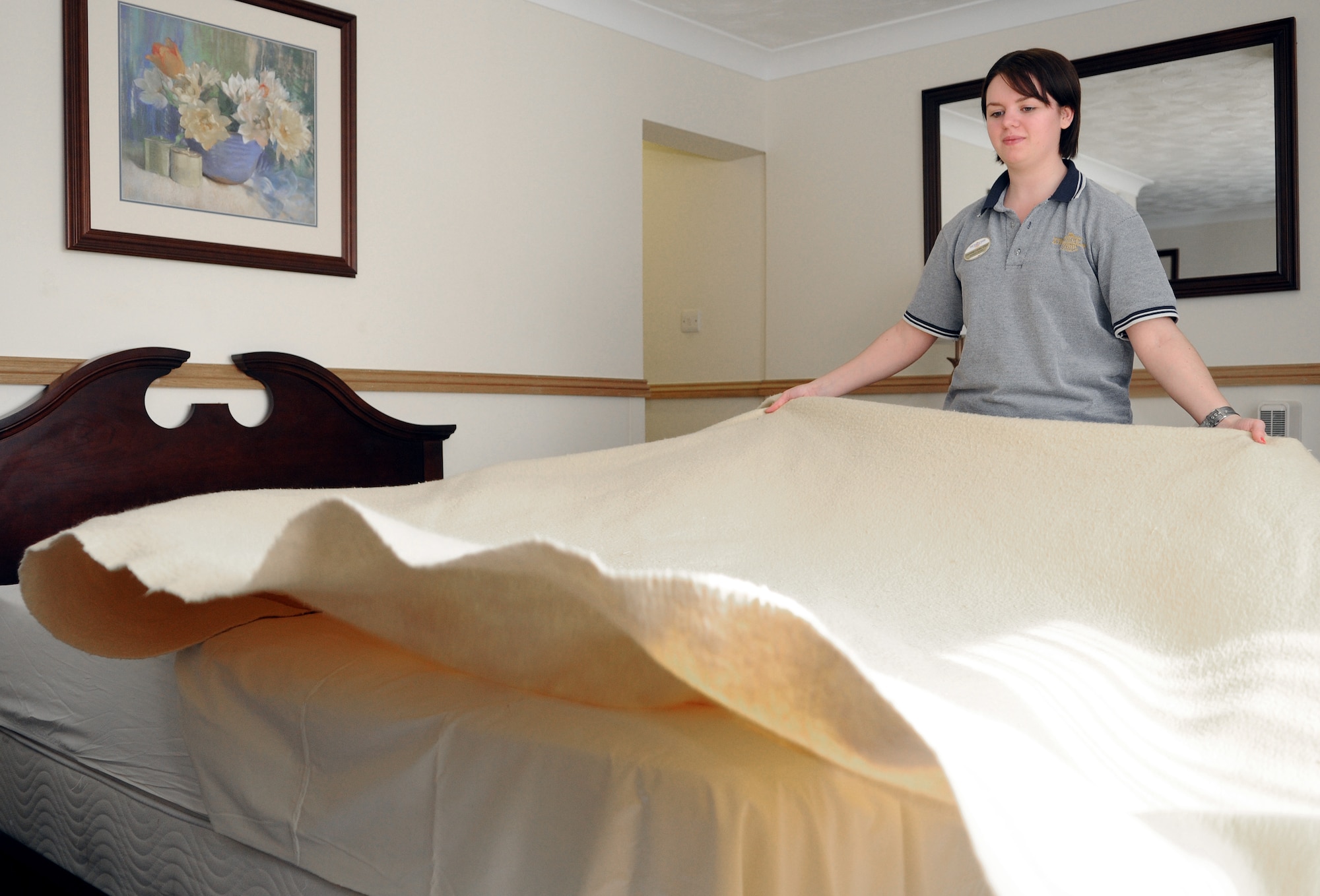 RAF MILDENHALL, England -- Corrinne Lucas, Gateway Inn housekeeper, lays out new linens in a guest room at the lodging facility here April 6. As part of their annual accreditation process, the lodging staff is graded against Air Force standards on 114 checklist items from customer service to room quality. (U.S. Air Force photo/Staff Sgt. Thomas Trower)