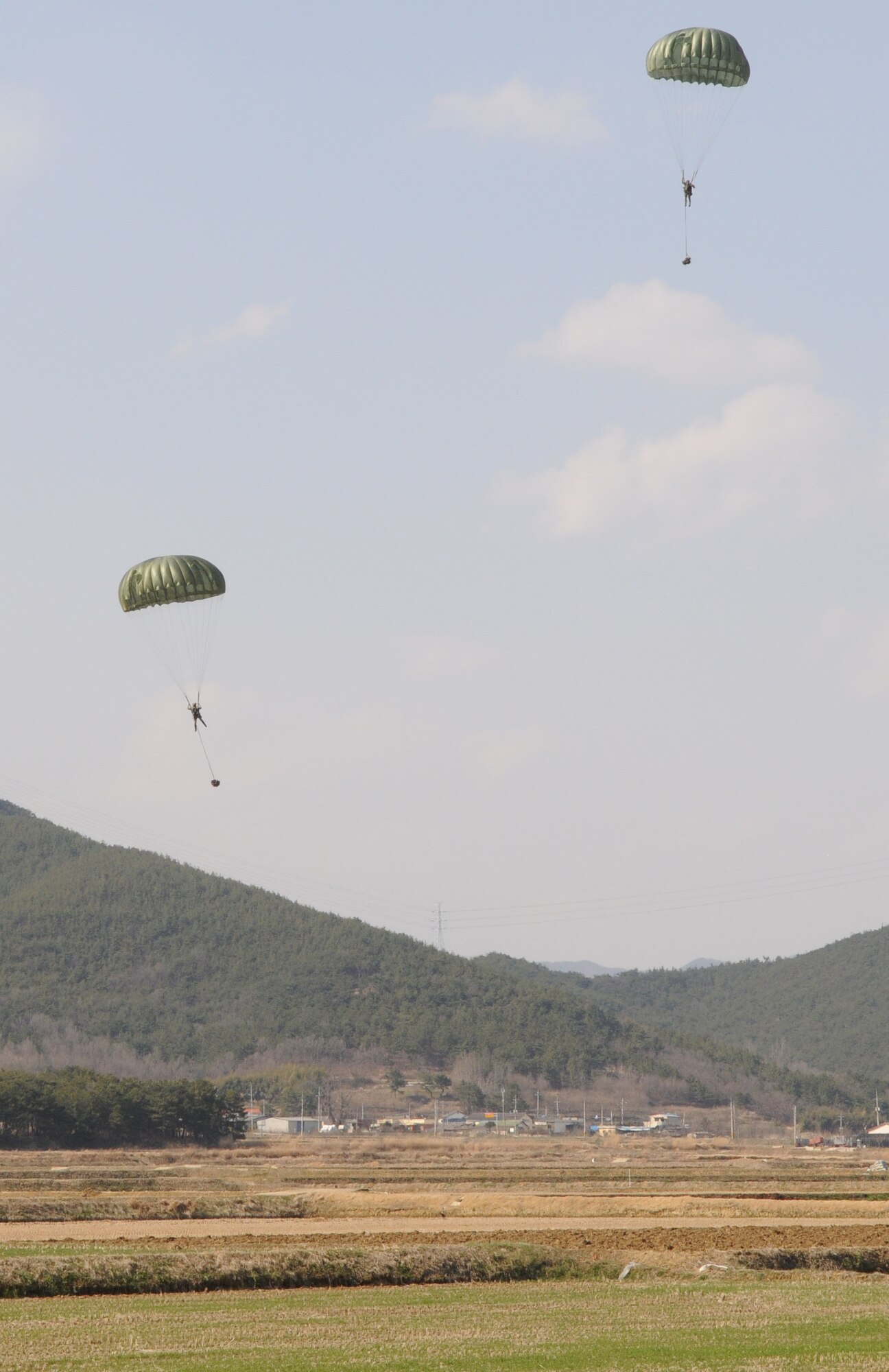 NEAR AN’GANG, Republic of Korea -- Pararescuemen from the 320th Special Tactics Squadron glide to the ground with their equipment after parachuting from a MC-130P Combat Shadow during a combat search and rescue exercise here March 26. The pararescuemen had to locate and treat two simulated wounded aircrew members before calling for evacuation during the scenario.  The scenario is part of the 353rd Special Operations Group’s annual operational readiness exercise. (U.S. Air Force photo by Tech. Sgt. Aaron Cram)