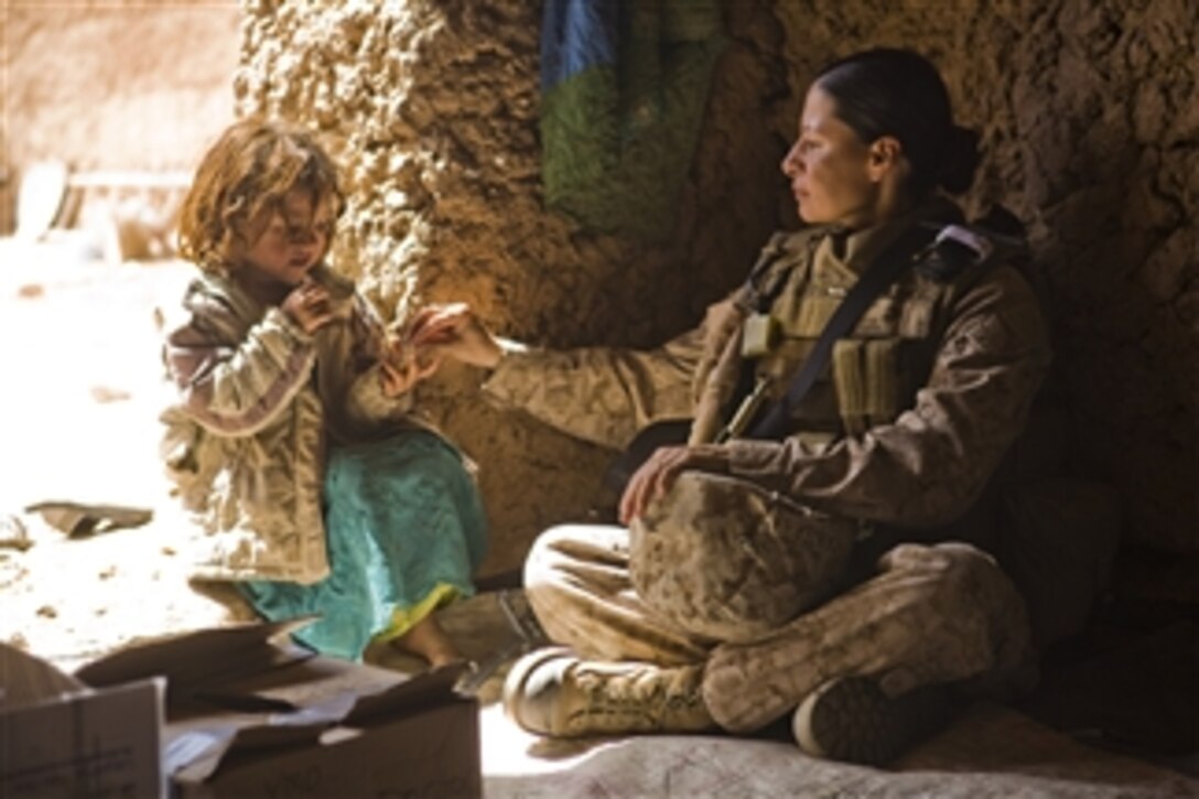 U.S. Marine Corps 1st Sgt. Raqual Painter gives candy to an Afghan girl while the girl's mother receives medical attention from U.S. Navy Lt. Michelle Lynch as part of a medical outreach program in the village of Now Abad in Helmand province, Afghanistan, on March 15, 2010.  The clinic is being conducted by the Female Engagement Team with Marine Expeditionary Brigade-Afghanistan.  