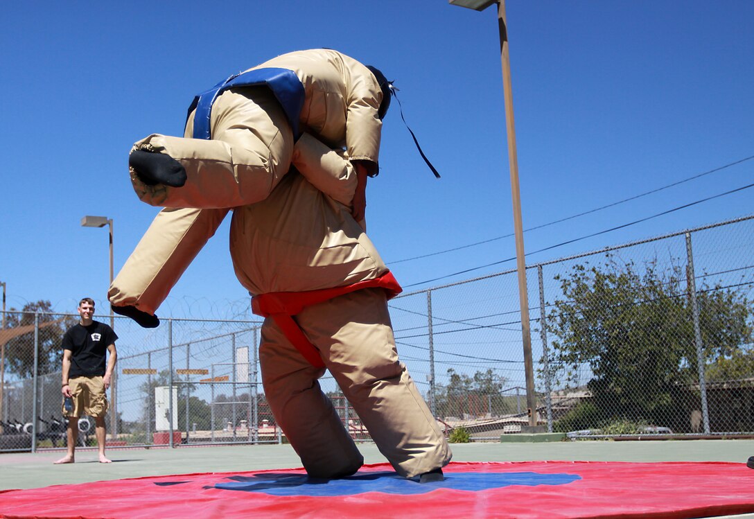 Seaman Adam W. Smith, corpsman, 1st Battalion, 1st Marine Regiment, 1st Marine Division, throws Lance Cpl. Tony J. Dipraseuth, fitness specialist, Semper Fit Division, Marine Corps Community Services, during the Single Marine Program’s Sumo Wrestling Tournament at Camp Pendleton’s 53 Area Gym, April 7. The lunch-time tournament was the first of its kind and maintained the SMP's mission to continually support troop welfare. The event also provided single service members with a rock wall and a free lunch.