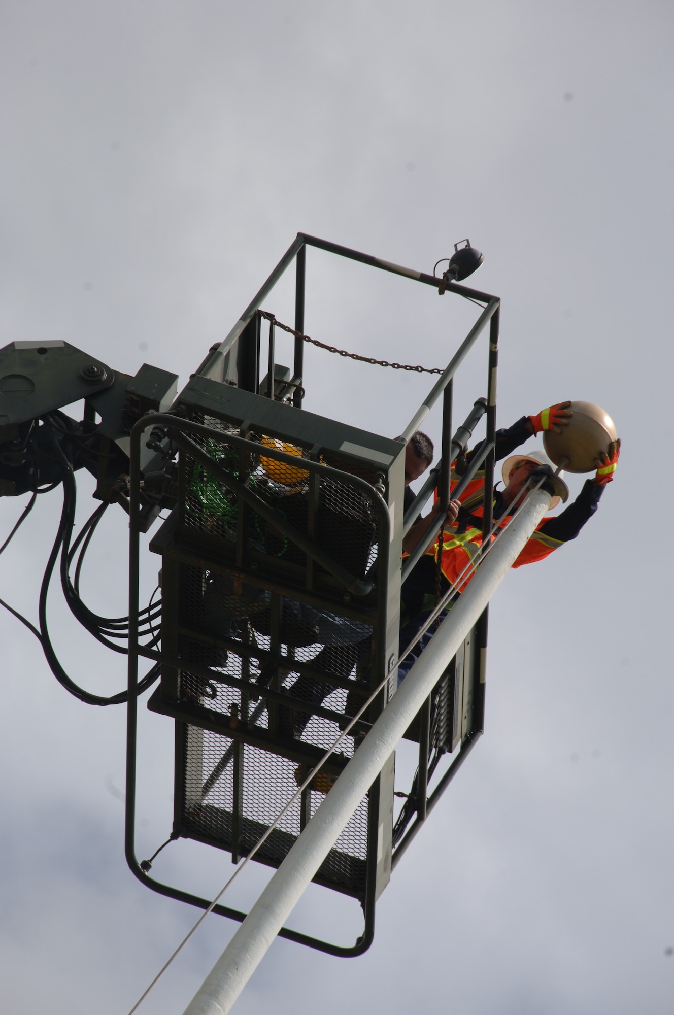 Mr. Art Garde, 15th Civil Engineer Squadron high voltage electrician (white helmet), and Mr. Ted Harjo, 15 CES maintenance mechanic, are lifted by a "Condor" vehicle to remove the "truck" from the flag pole after the wind dislodged it Apr. 6 at Hickam Air Force Base, Hi. (U.S. Air Force photo by Senior Airman Nathan Allen)