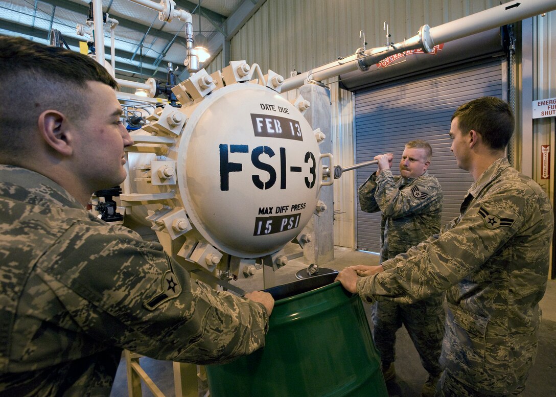 Staff Sgt. Blake Walker, 316th Civil Engineer Squadron water and fuel systems craftsman, uses a ratchet wrench to loosen a nut on the filter separator constant pressure system inside a Navy Reserve fuel facility, as Airman James Porter, left, 316 CES water and fuel systems apprentice, and Airman 1st Class William Carmichael, 316 CES water and fuel systems apprentice, tilt a fuel drum to catch the fuel spillage at Joint Base Andrews, Md., March 30, 2010. (U.S. Air Force photo by Bobby Jones)