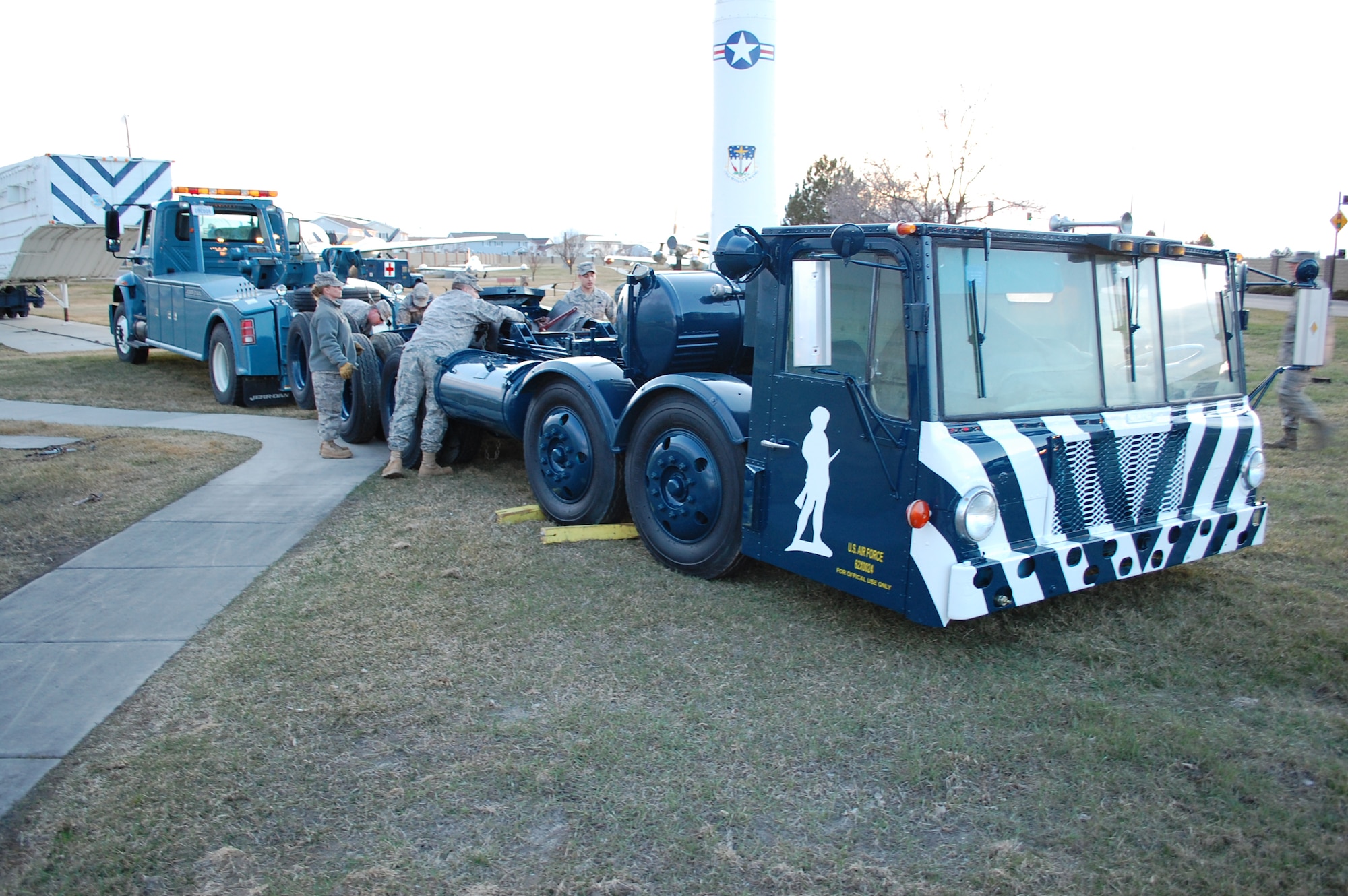 Members of the 341st Logistics Readiness Squadron work to unhook the Transporter Erector from the towlines used to move it from the Allied Trades Shop back to its location at the Malmstrom Museum. (U.S. Air Force photo/Airman 1st Class Kristina Overton)