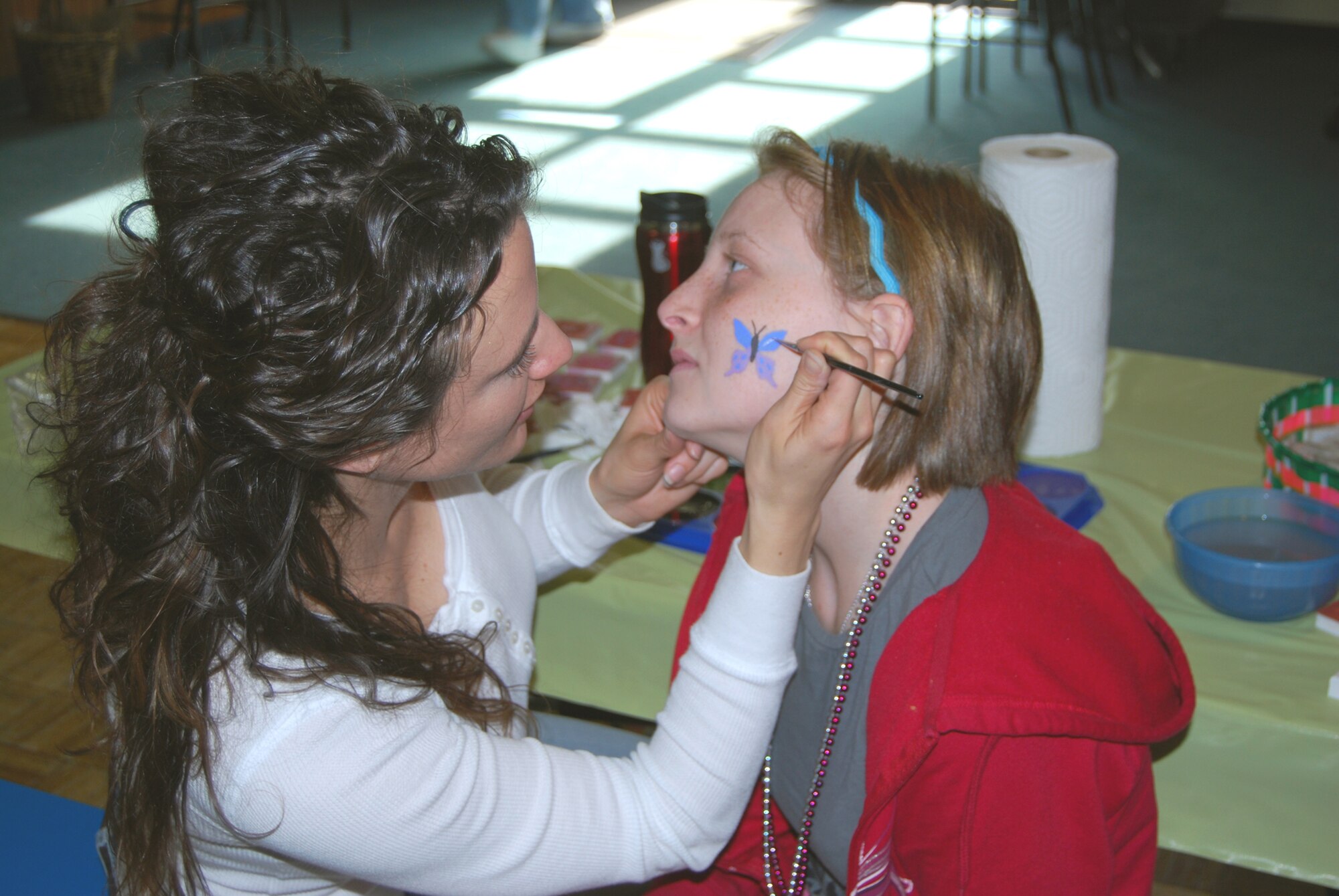 Tiffany, 15, has a butterfly painted on her face by Annie Gardner, Youth Center school age coordinator, at the Spring Carnival April 3.(U.S. Air Force photo by/Airman 1st Class Kristina Overton)