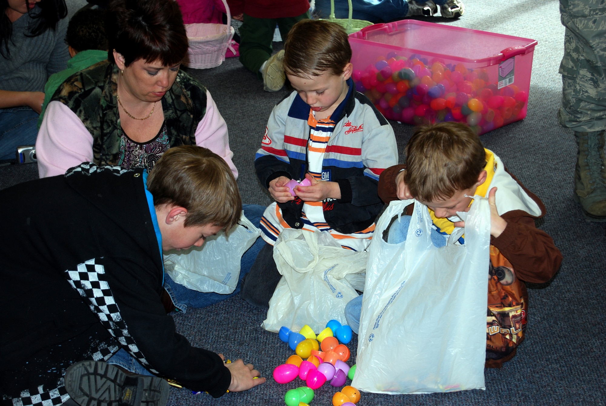 Kim Powers and sons Bryer, 10, and Aden and Ashton, 5, sort through and collect the candy from their Easter eggs after the Easter Egg Hunt at the Base Chapel April 3.(U.S. Air Force photo/Airman 1st Class Kristina Overton)