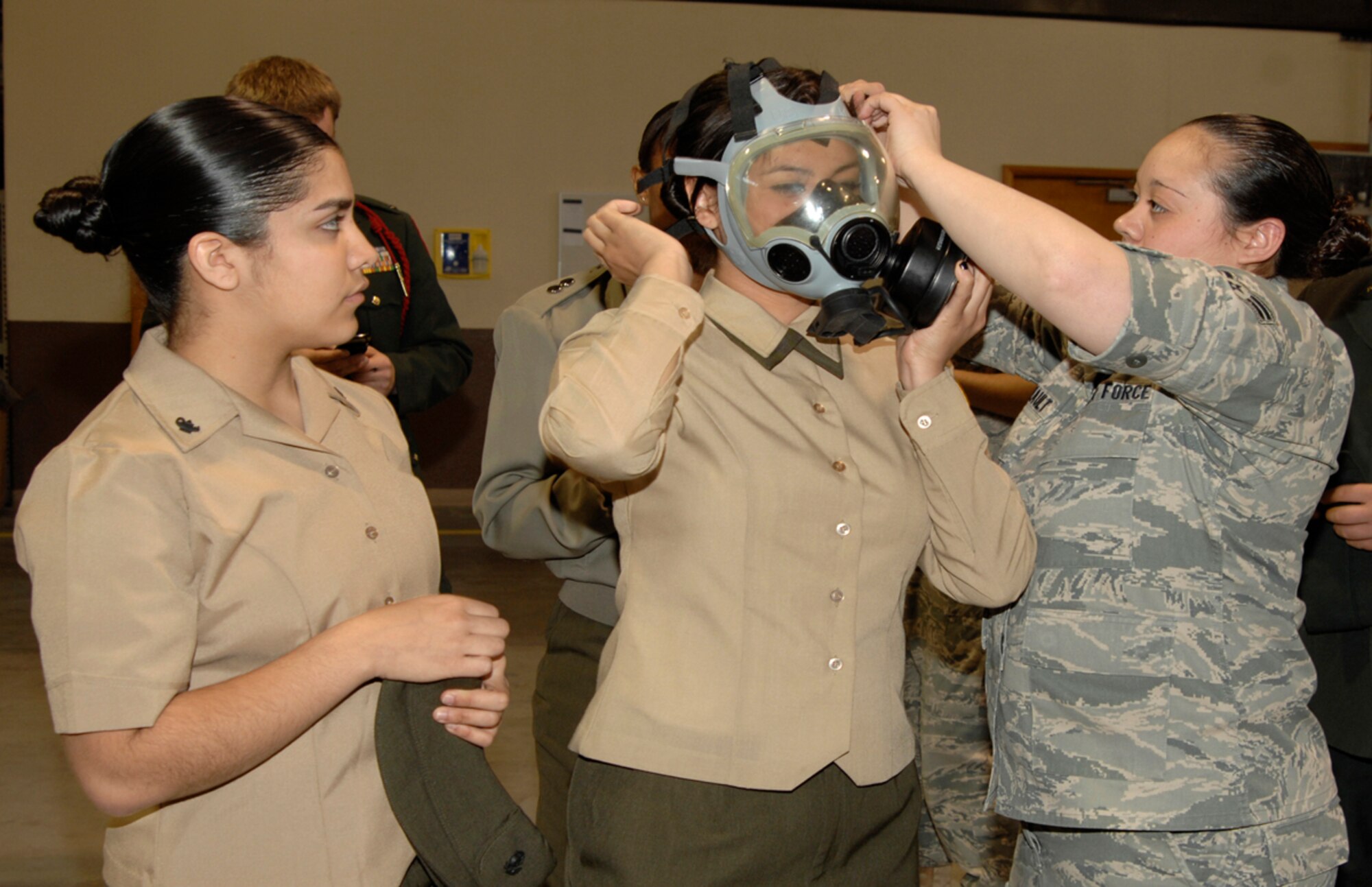 Airman 1st Class Megan Tetreault, 22nd Logisitcs Readiness Squadron Individual protective equipment technician, helps Viviana Miranda, Marine Junior Reserve Officers’ Training Corps cadet from Wichita’s Northeast Magnet High School, don a gas mask at the 22nd Logistics Readiness Squadron’s IPE warehouse, during a JROTC tour April 7, 2010, McConnell Air Force Base, Kan. Airman Tetreault answered the high school students’ questions about the IPE and demonstrated how individual pieces functioned. The students toured the base to better understand the variety of careerfields at McConnell and how they support the base's refueling mission.