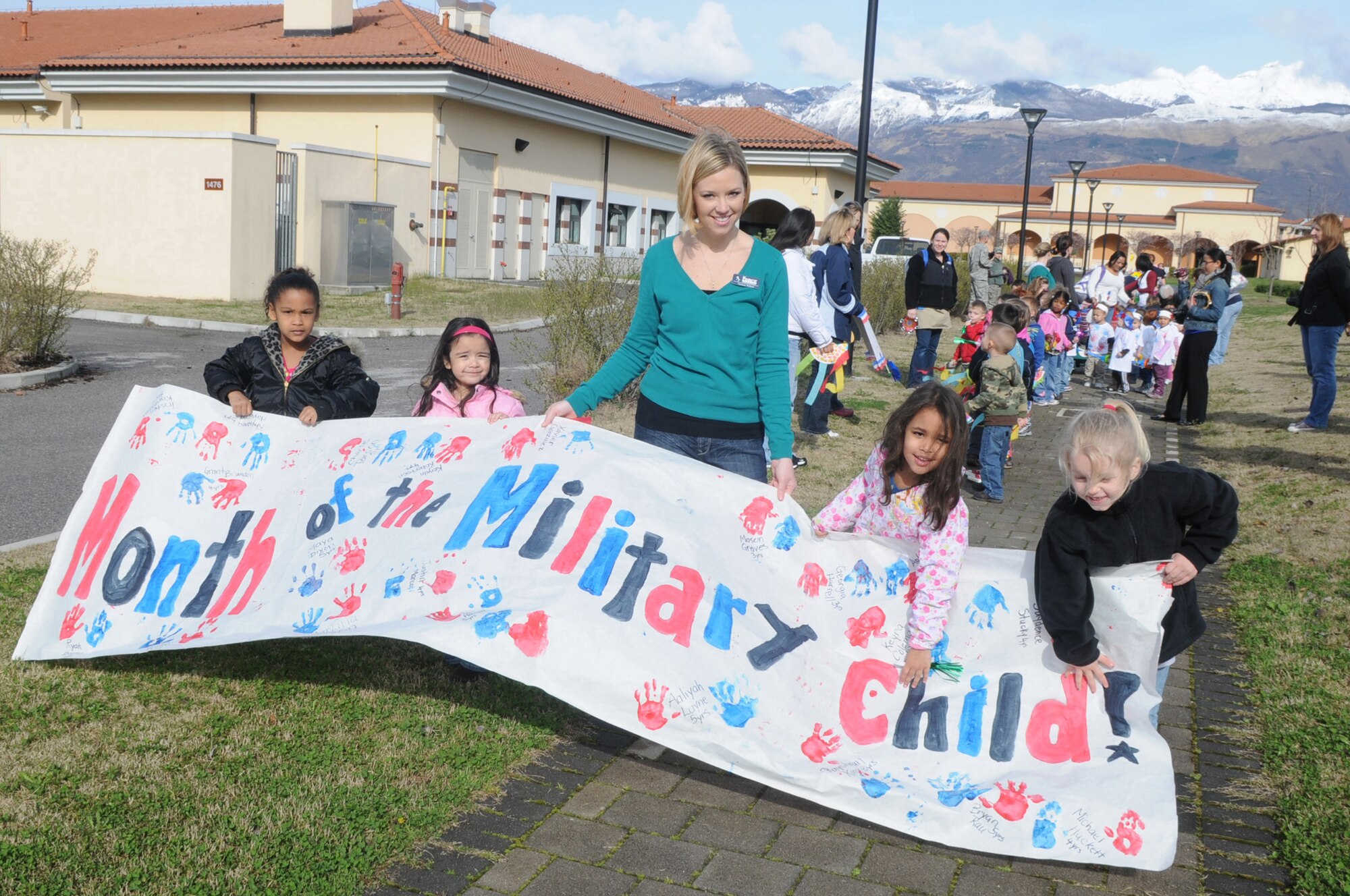 Melissa Waters Staff Member, Area F Child Development Center, helps a group of preschool children hold a banner they made for April's Month of the Military Child. Children ages 6 months to 5 years participated in the day's events, which included lunch with parents, friends and family April 2.
(U.S. Air Force photo/ Staff Sgt. MercedesKimble Crossland)