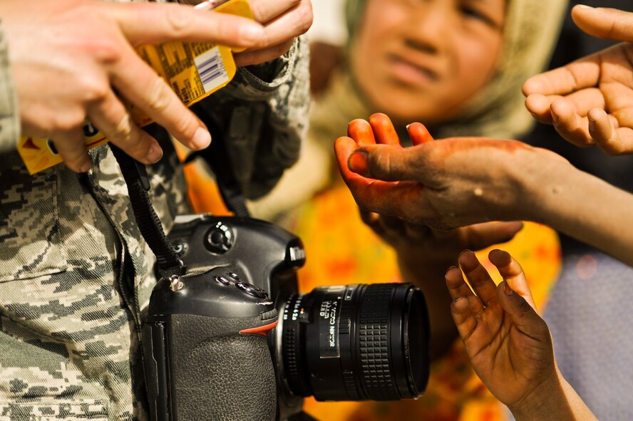 Staff Sgt. Christine Jones gives candy to Afghan children waiting to receive medical treatment March 16, 2010, at Lindenau Clinic in Main Operating Base Price, Helmand province, Afghanistan. Sergeant Jones is a photographer with 4th Combat Camera Squadron. (U.S. Air Force photo/Tech. Sgt. Efren Lopez)