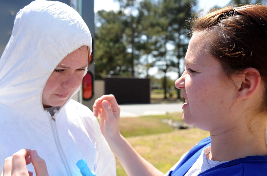 MOODY AIR FORCE BASE, Ga. -- Airmen 1st Class Jennifer Forsythe, 23rd Aeromedical Dental Squadron bioenvironmental journeyman, adjusts the hood of a protective suit for Senior Airman Sarah Cox, 23rd AMDS bioenvironmental journeyman, during the Air Combat Command Chemical, Biological, Radiological and Nuclear Challenge here April 6. Airmen in hazardous chemical environments are required to wear a protective suit, nitrile gloves and rubber boots to prevent contamination to any of the hazardous chemicals in the environment. (U.S. Air Force photo by Airman 1st Class Joshua Green/RELEASED)