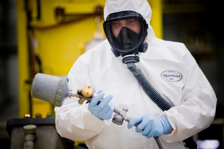 Tech Sgt. Anthony Nowak, 62nd Maintenance Squadron, breathing through a respiratory system and outfitted in a tyvek suit for safety, readies a high volume low-pressure paint sprayer at McChord Field's Corrosion Control facility Thursday. (U.S. Air Force Photo by Abner Guzman)
