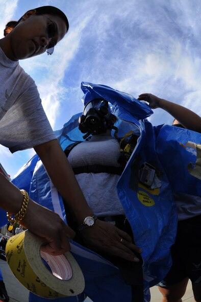 MOODY AIR FORCE BASE, Ga. -- Tech. Sgt. Ronnece Spencer and Senior Airman Amanda Goralski, 23rd Aeromedical Dental Squadron Bioenvironmental Flight, assist Senior Airman Sarah Cox, 23rd AMDS bioenvironmental journeyman, whiles she puts on a chemical suit during the Air Combat Command Chemical, Biological, Radiological and Nuclear Challenge here April 7. The suit is fully encapsulated and protects a person from all outside vapors. (U.S. Air Force photo by Airman 1st Class Benjamin Wiseman/RELEASED)